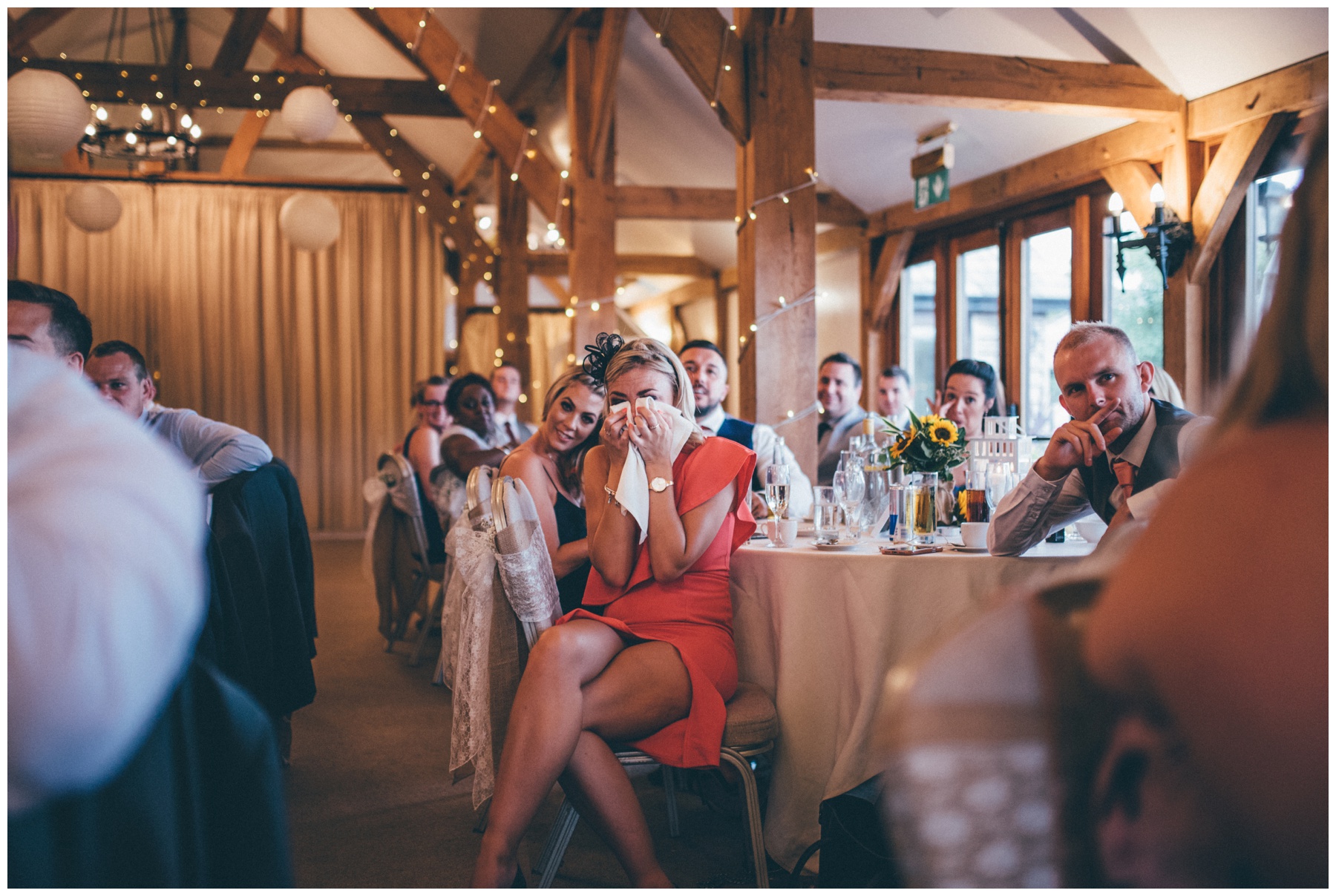Female wedding guest cries into a napkin during the speeches at Sandhole Oak Barn in Cheshire.