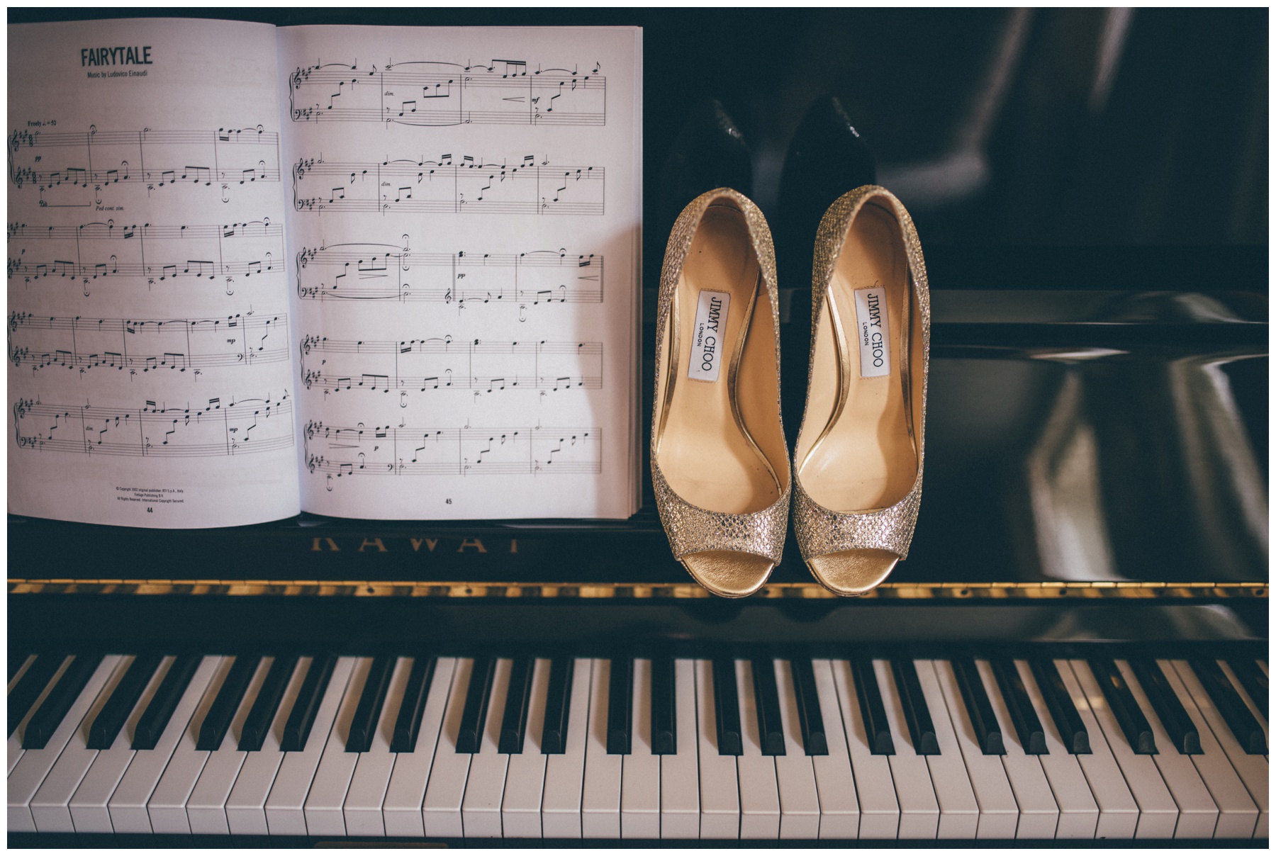 Gold and sparkly Jimmy Choo wedding shoes against a backdrop of a grand piano ahead of a Cheshire wedding at Merrydale Manor.