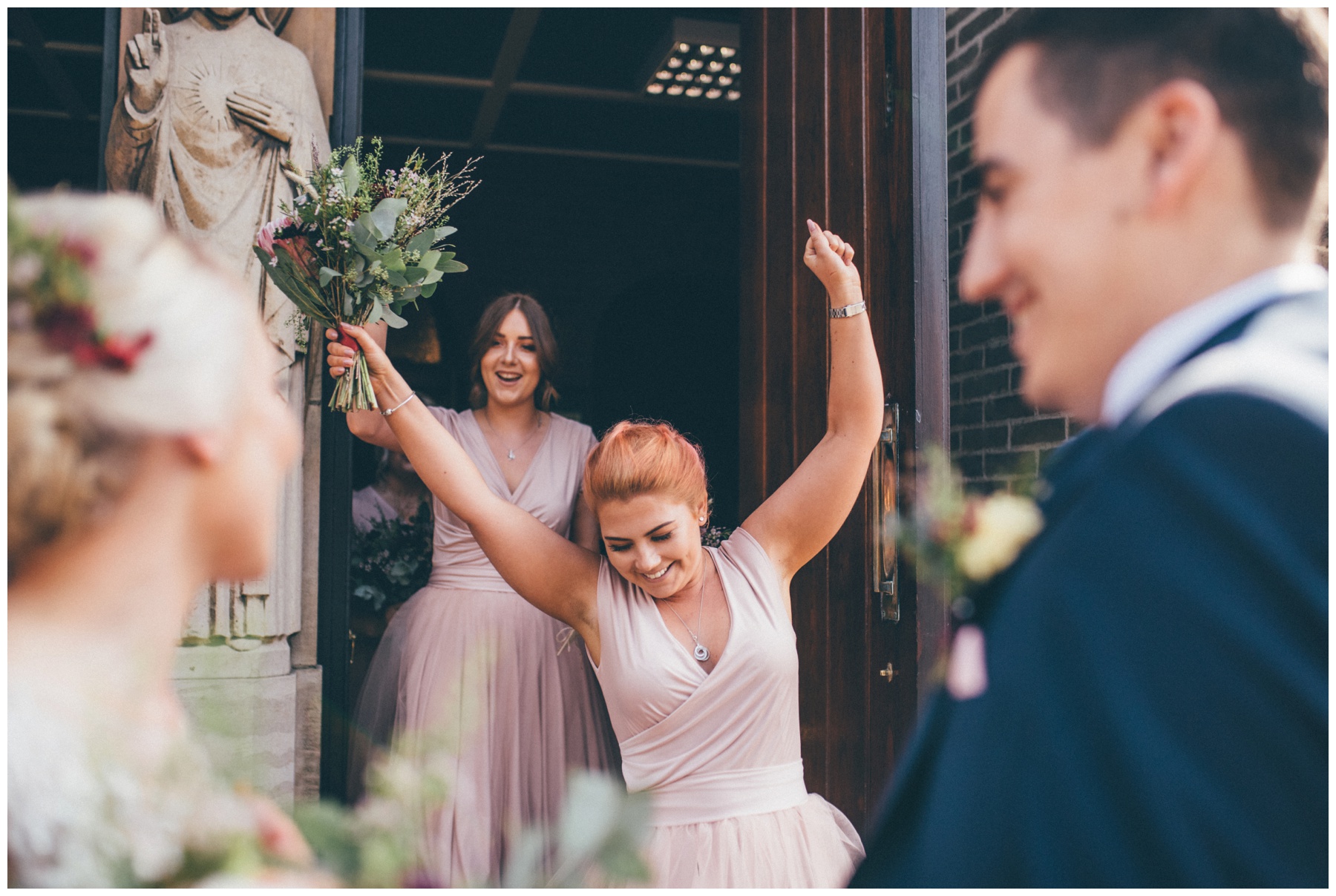 Bridesmaid celebrates the newlyweds at she walks out of church cheering after the wedding in Sheffield.
