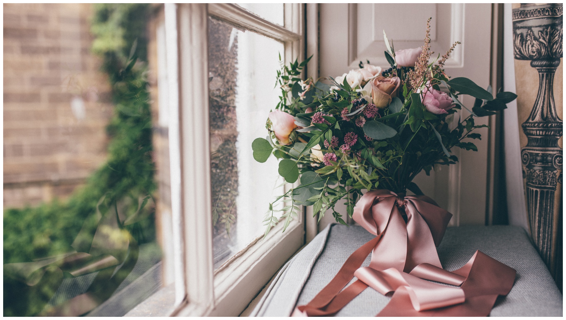 The most beautiful pastel and dusky pink wedding bouquet held together bye ribbons, in the window at Swinton Park Estate in Yorkshire.