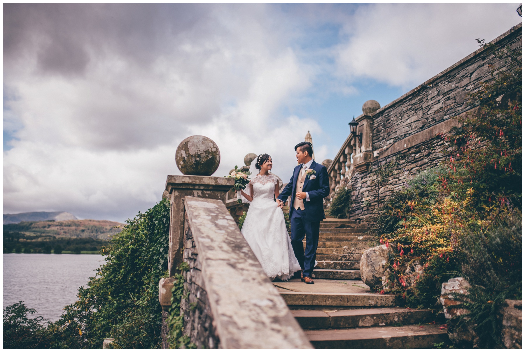 Bride and groom walk hand in hand through the grounds of Langdale Chase hotel in the Lake District.