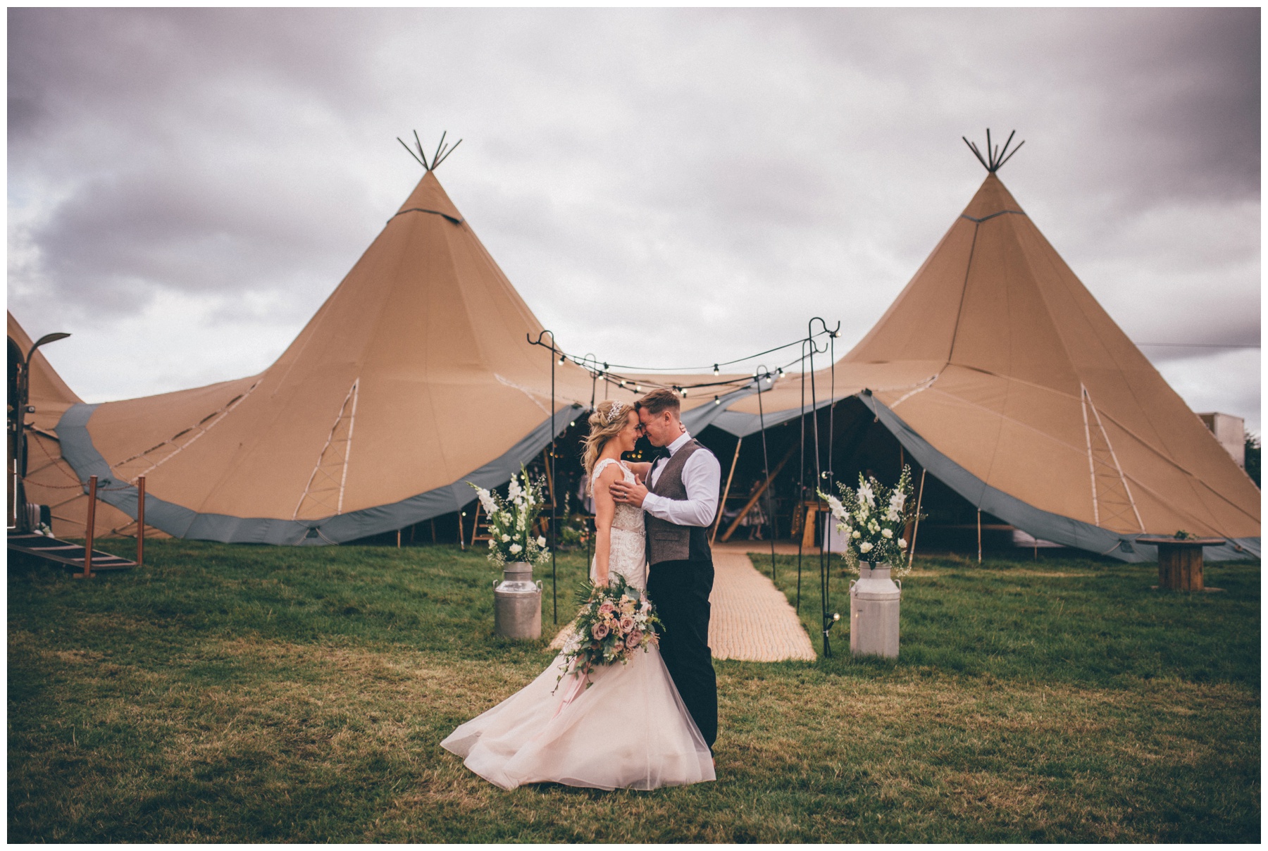 Bride in a blush pink wedding dress with her groom in a tweed suit share a kiss outside their wedding tipi in Staffordshire wedding.