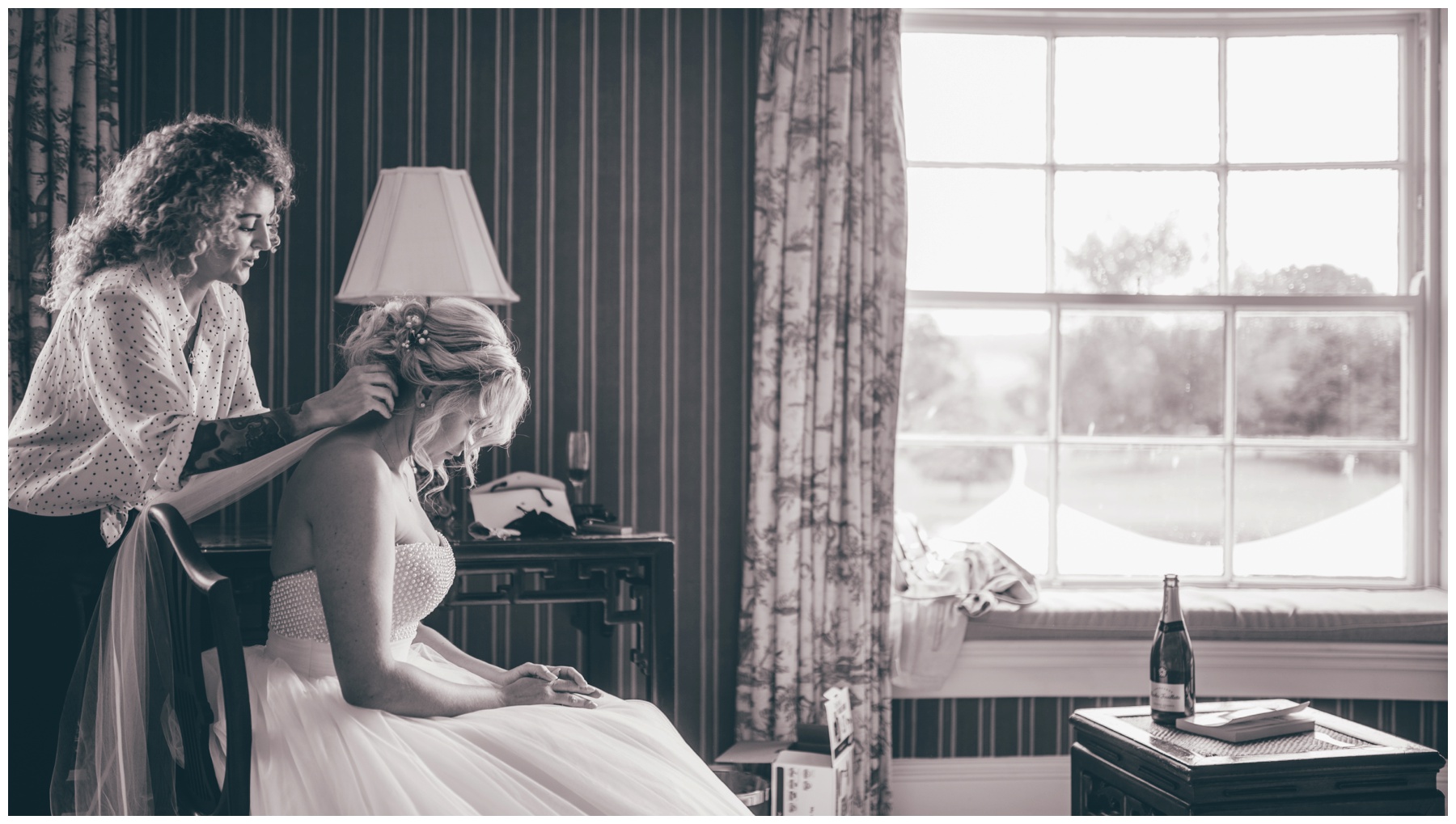 Wedding hairdresser puts the brides veil in and completes finishing touches on the beautiful bride at the Swinton Park Estate in Yorkshire.