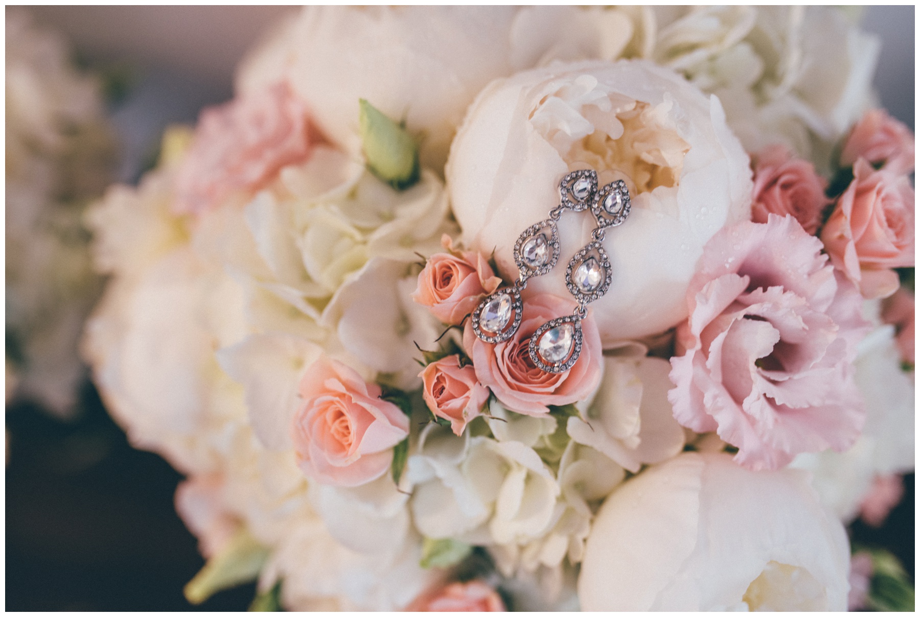 Brides stunning diamond earring against her beautiful wedding bouquet of peonies.