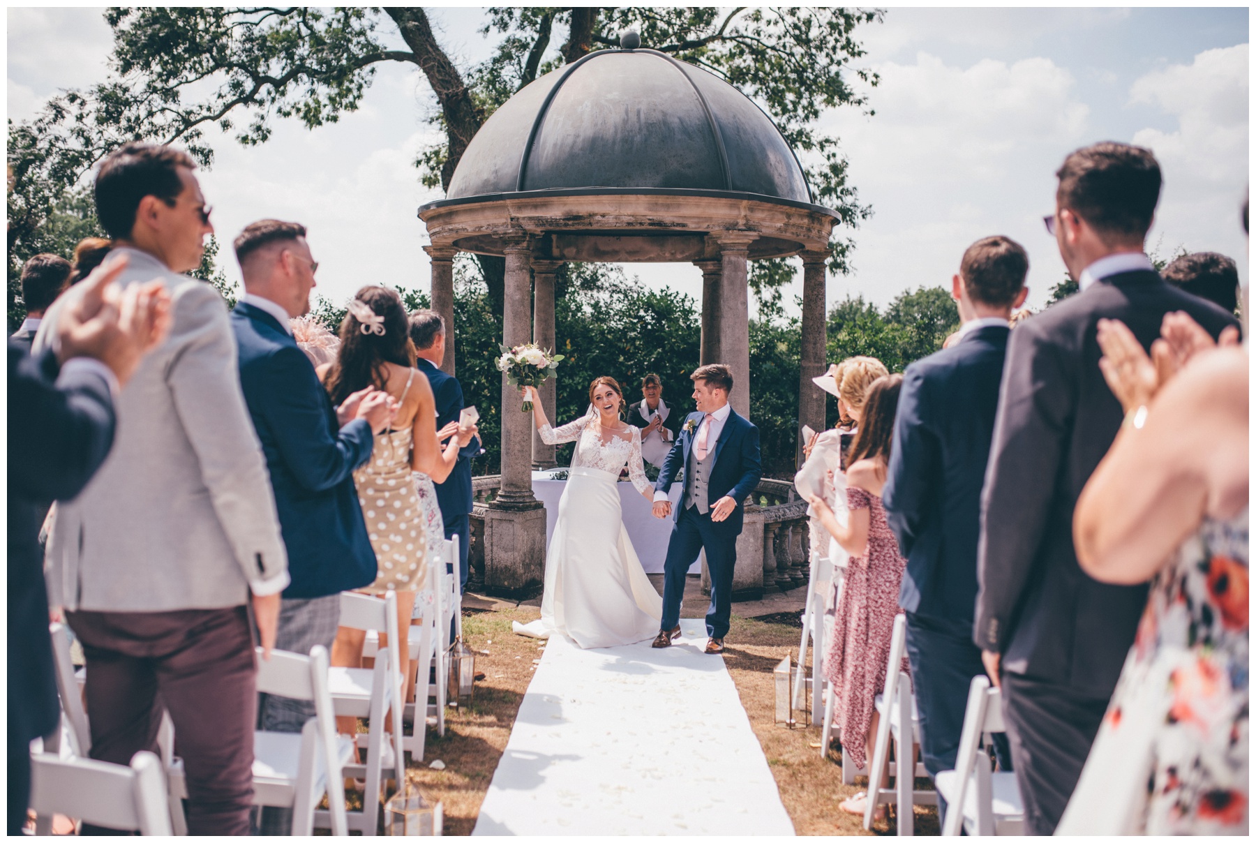 Bride and groom celebrate being announced as husband and wife at outdoor ceremony at Tilstone House.