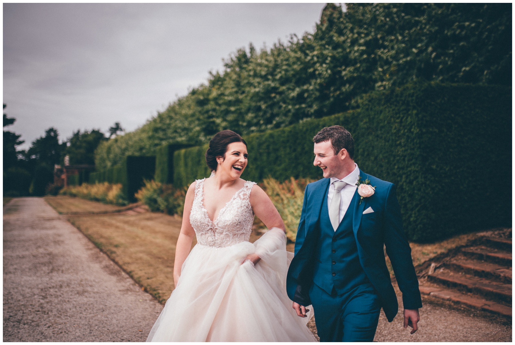 Bride and groom laugh in the gardens at Thornton Manor Cheshire wedding venue.