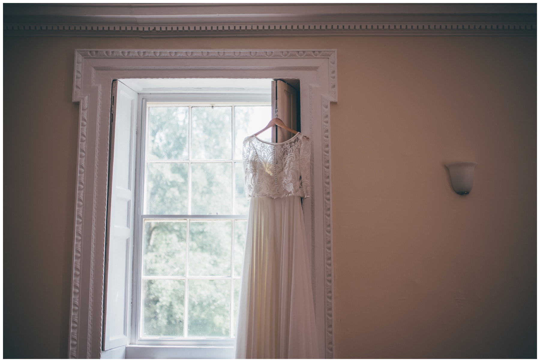 Bride's stunning two-piece wedding gown hung up at Trafford Hall in Cheshire.