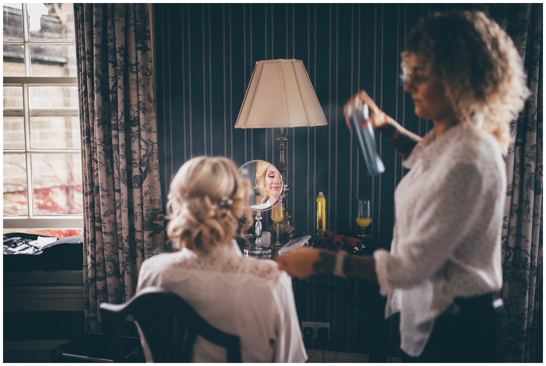 Stunning bridal reflection as the hairdresser does her hair on the wedding morning at Swinton Park Estate in Yorkshire.