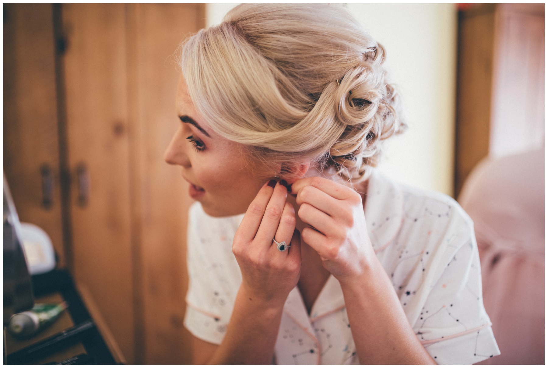 Bride puts on her sapphire and diamond earrings.