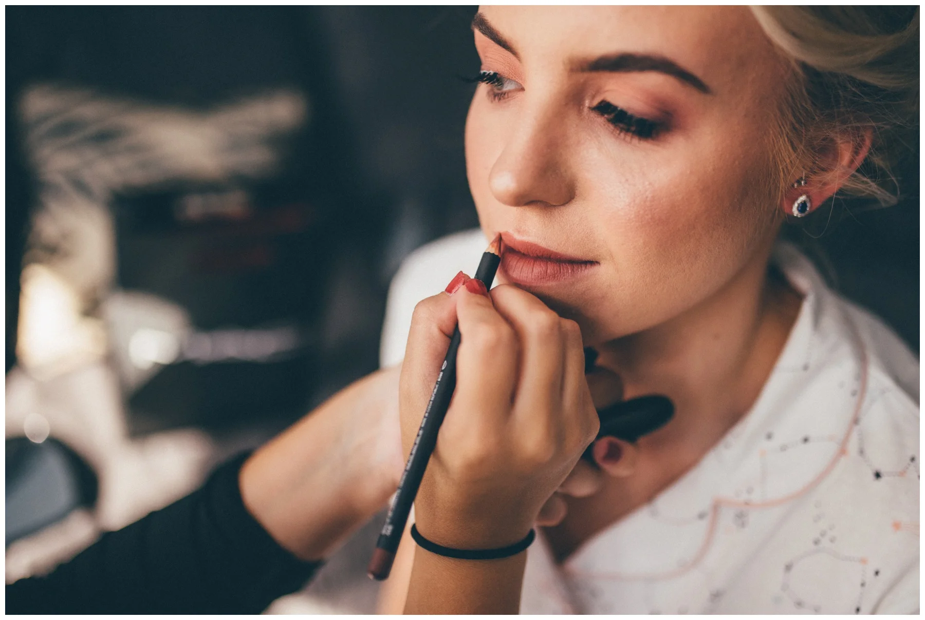 Beautiful bride gets her lipstick touched up before her wedding ceremony in Sheffield.