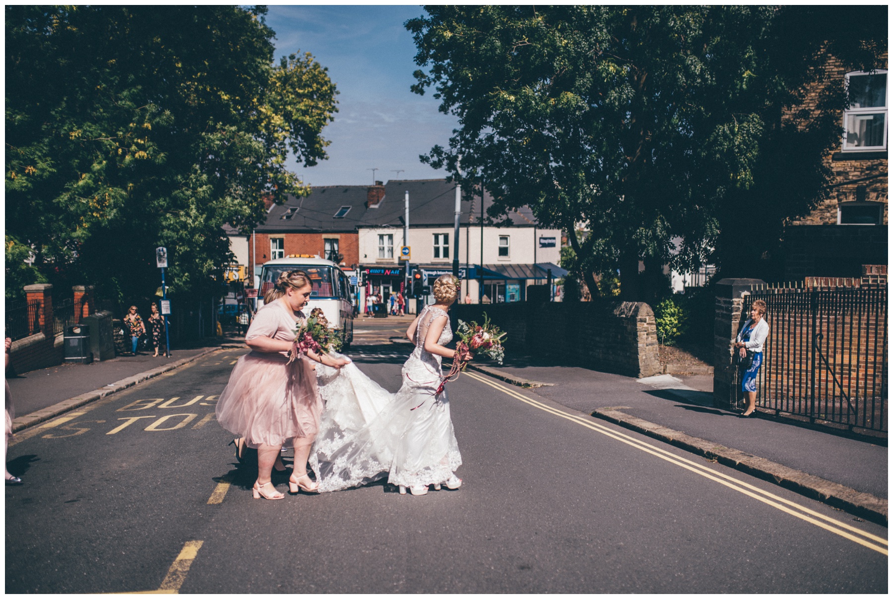 Bride gets helped across the busy city road by her bridesmaids.
