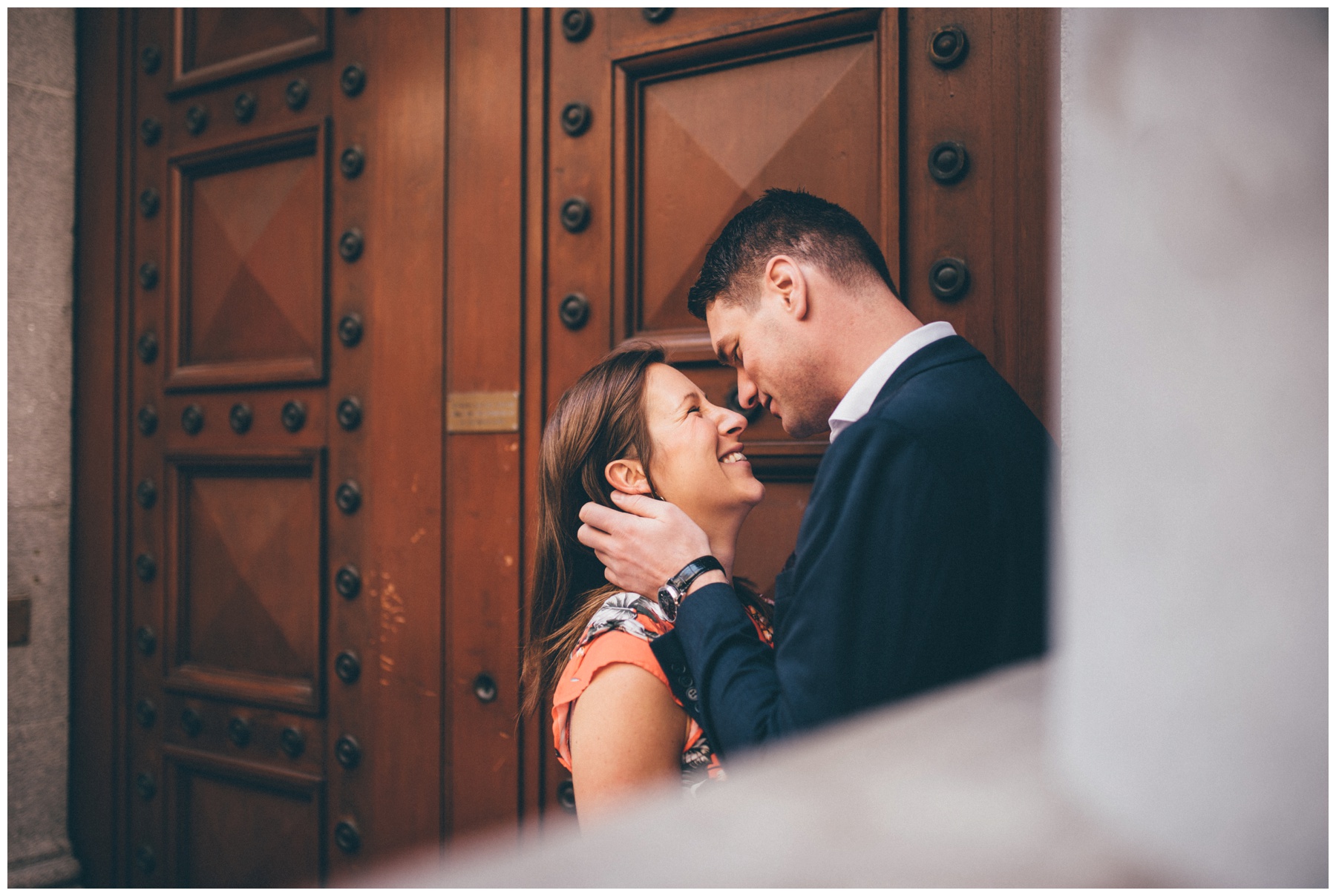 Couple kiss in a doorway during their engagement shoot in London city centre.