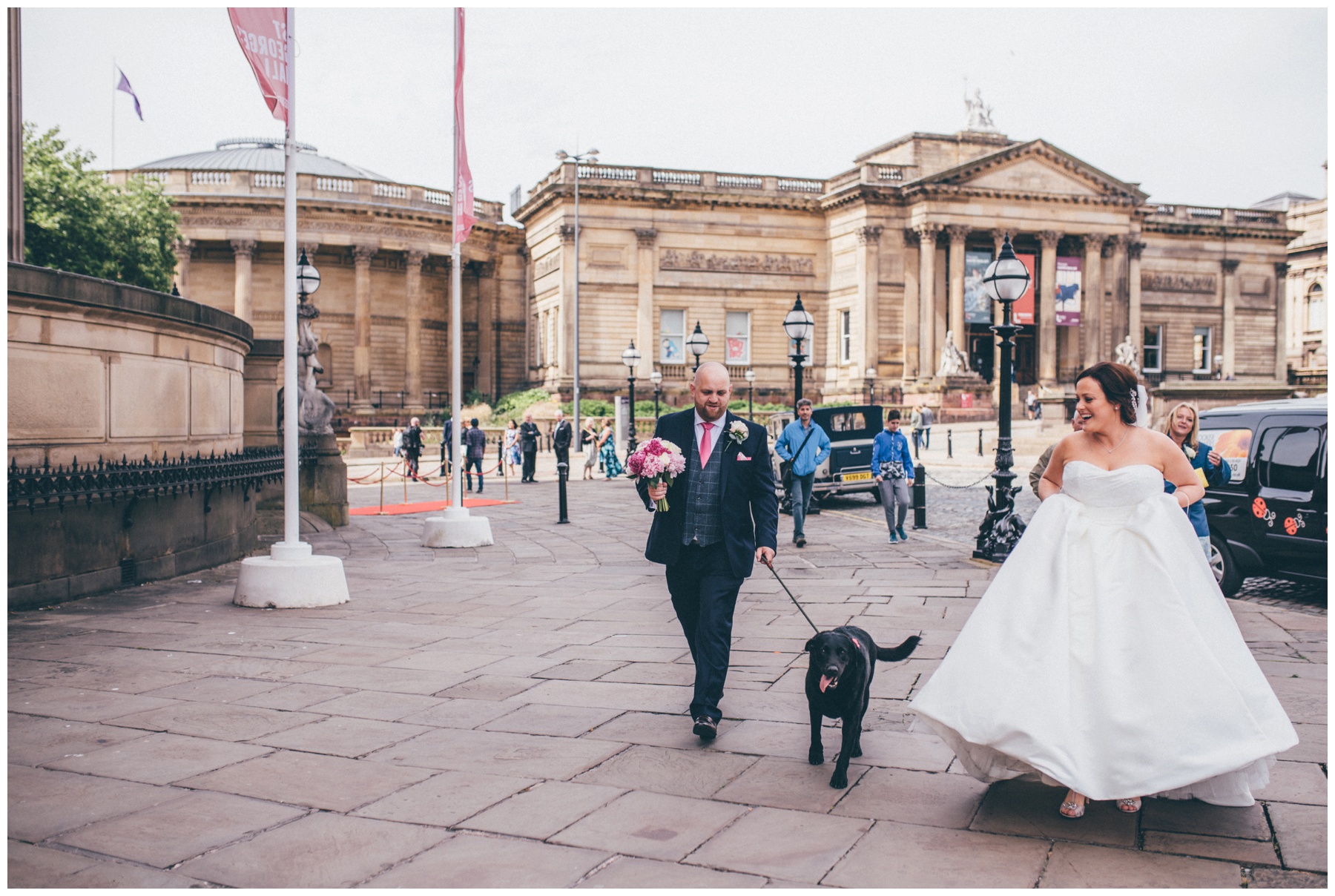 New husband and wife walk their dog in Liverpool city centre just after their wedding.