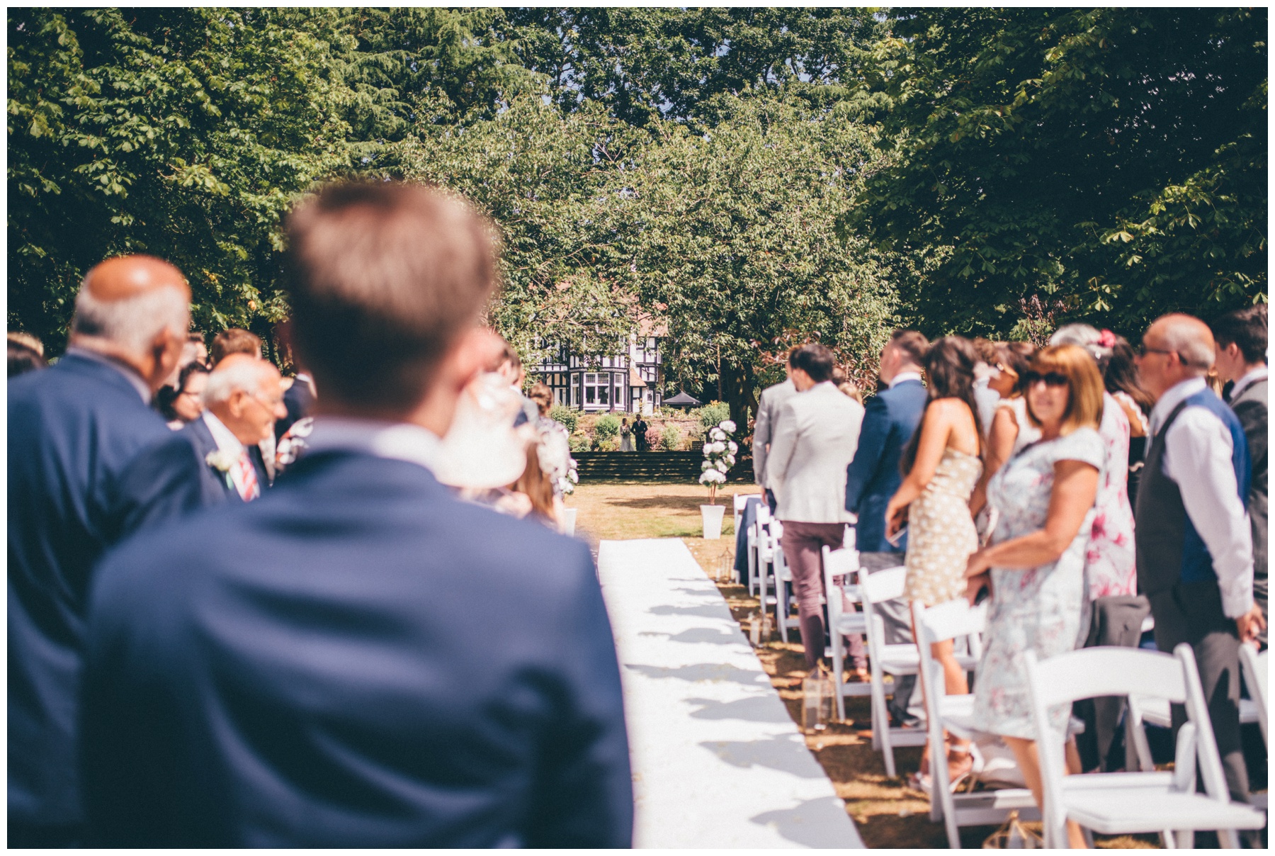Groom waits for his bride at the end of the aisle at Tilstone House in Cheshire.