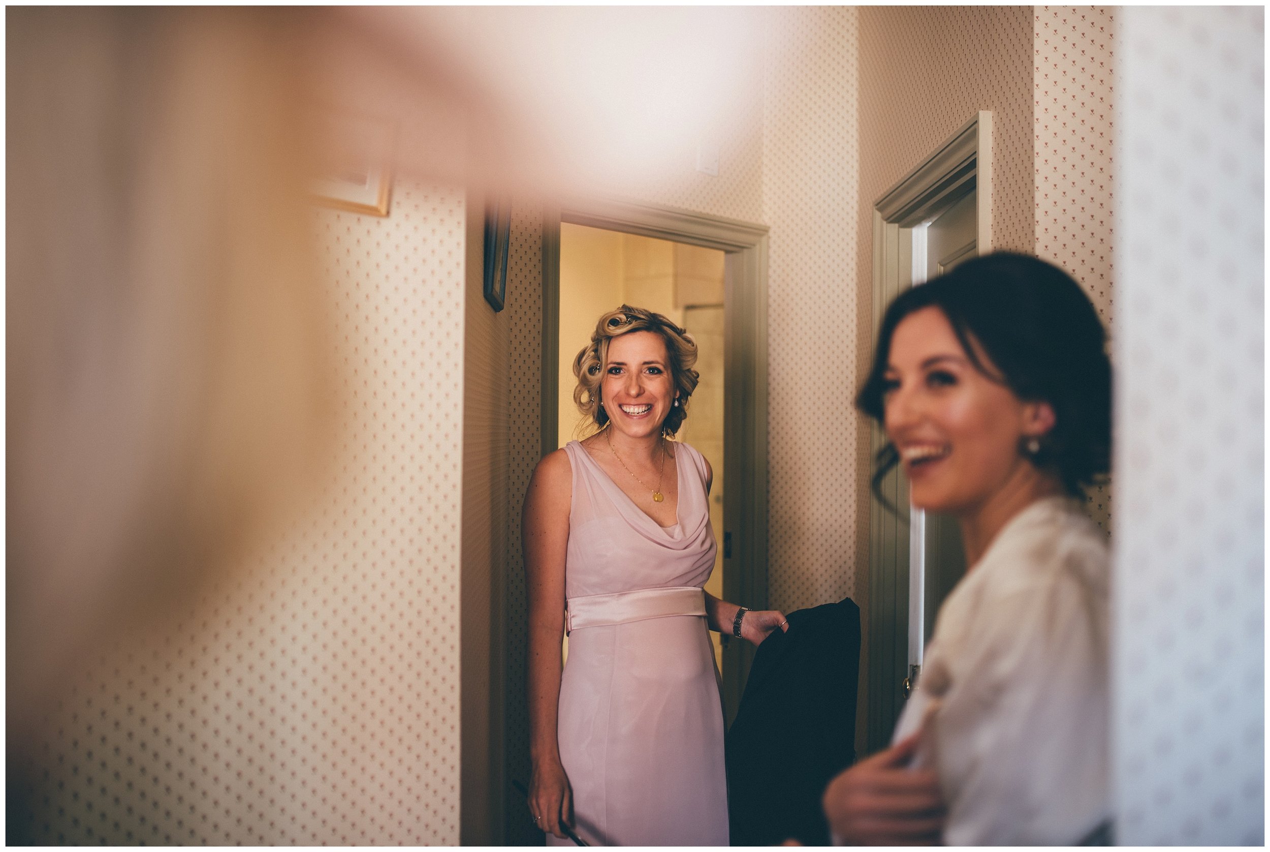 Bridesmaids dressed in dusky pink smile at the mother of the bride.