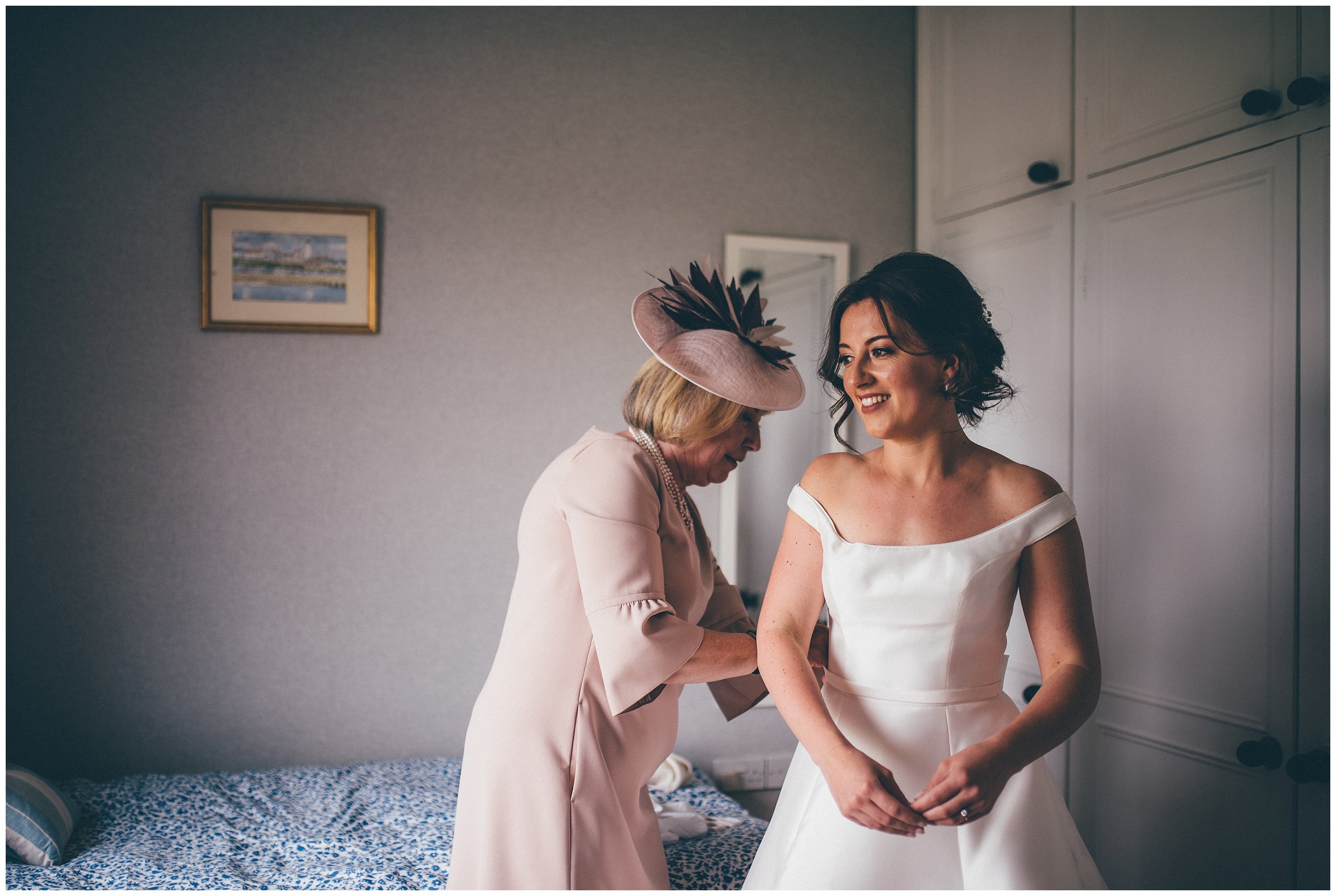 Bride gets helped into her wedding dress by her mum.