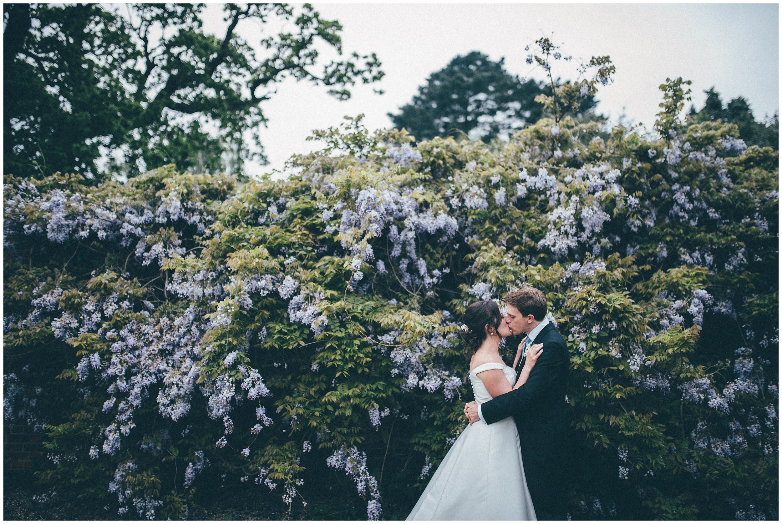 Bride and groom in front of beautiful flowers on their wedding day at Henham Park.