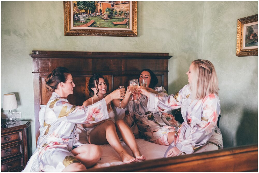 Bride cheers bridesmaids in bridal suite at Lake Garda wedding.