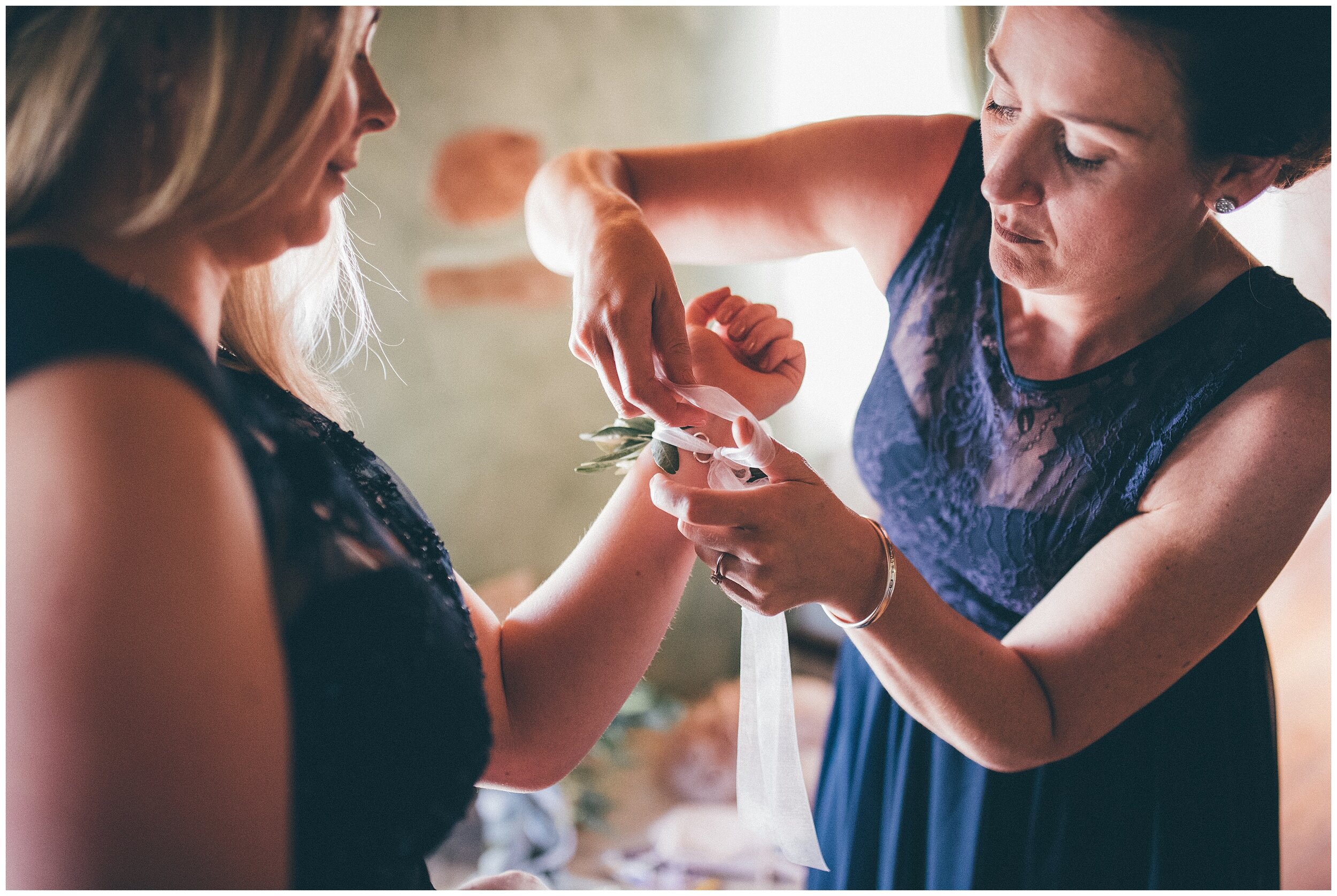 Bridesmaids help each other tie their flowers at Lake Garda wedding.