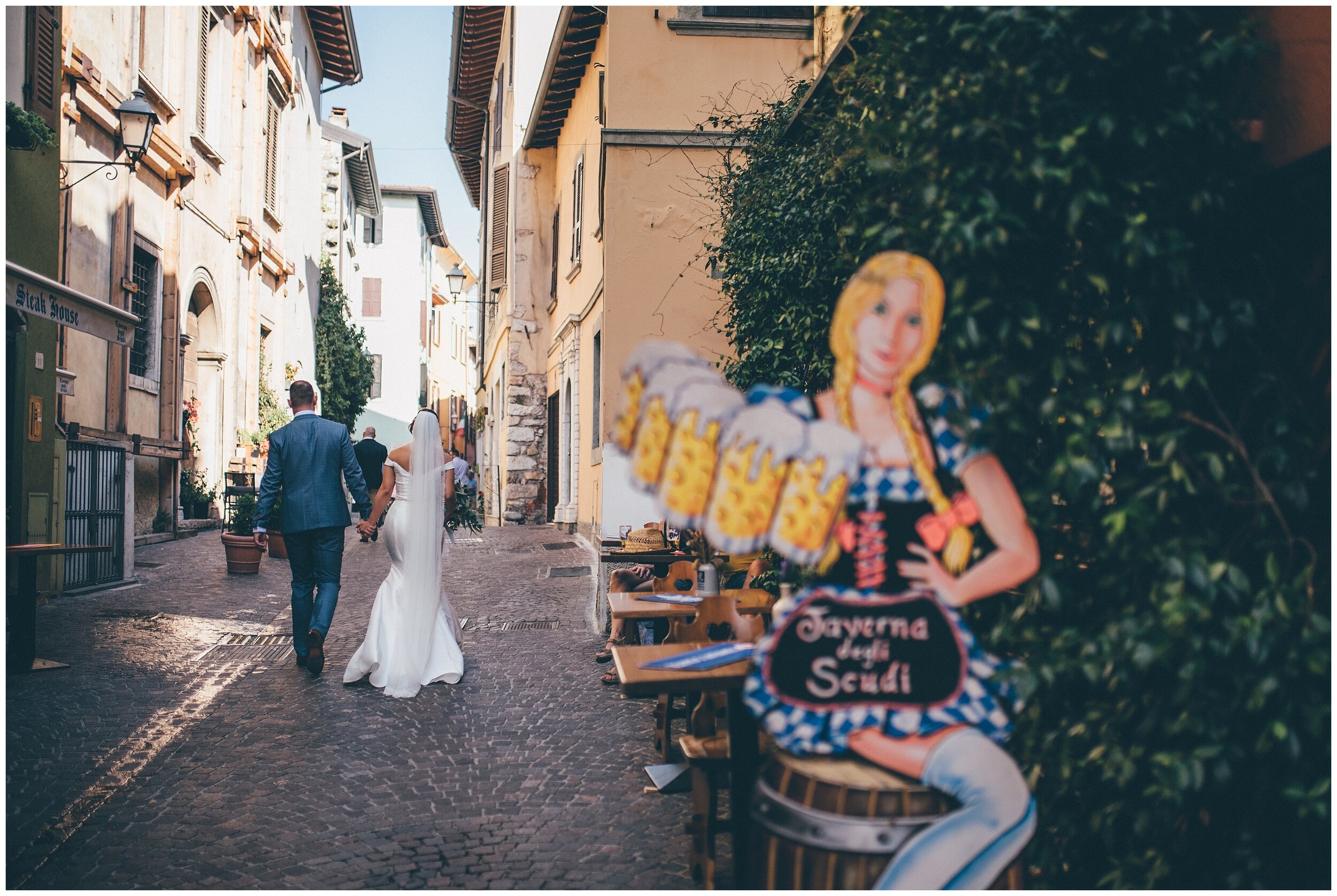 Newlyweds have their wedding photographs taken whilst strolling through Salo town centre in Lake Garda.