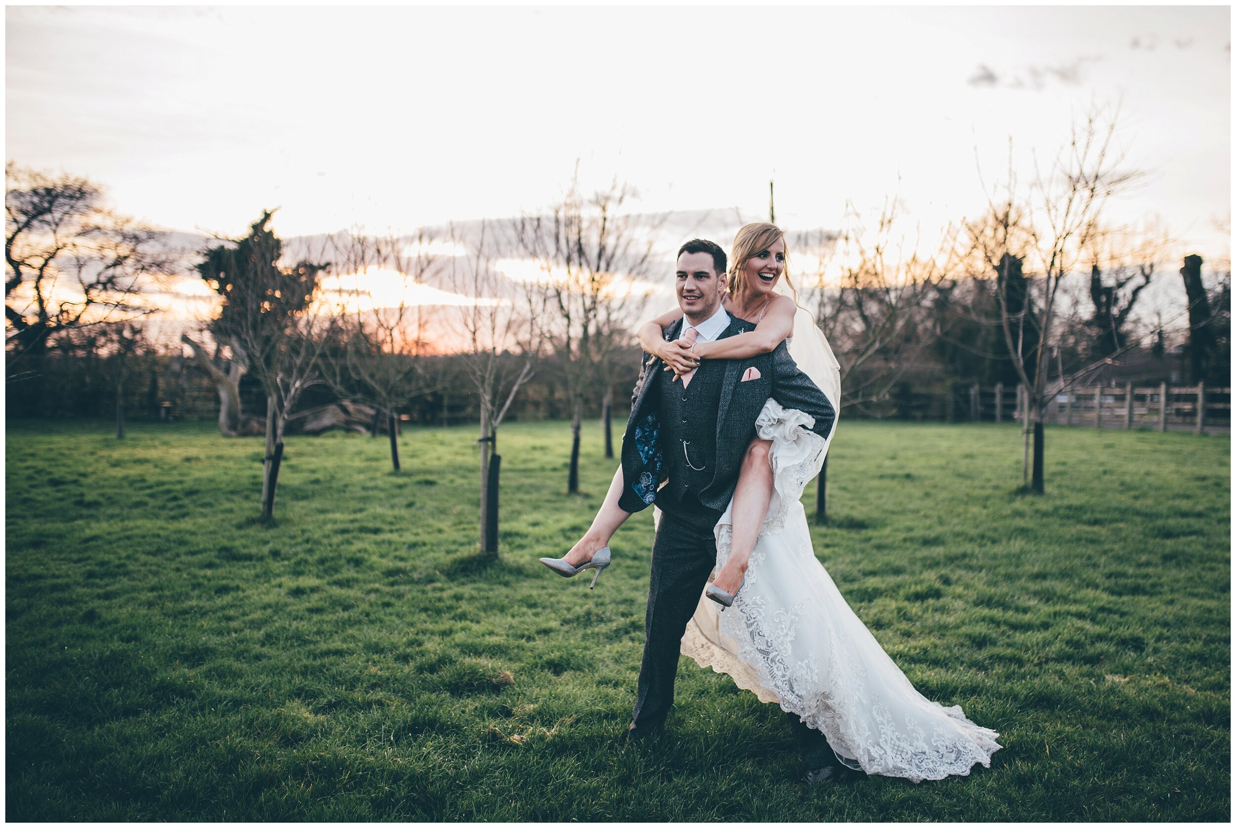 Groom gives his new wife a piggy back at Owen House wedding barn in Cheshire.