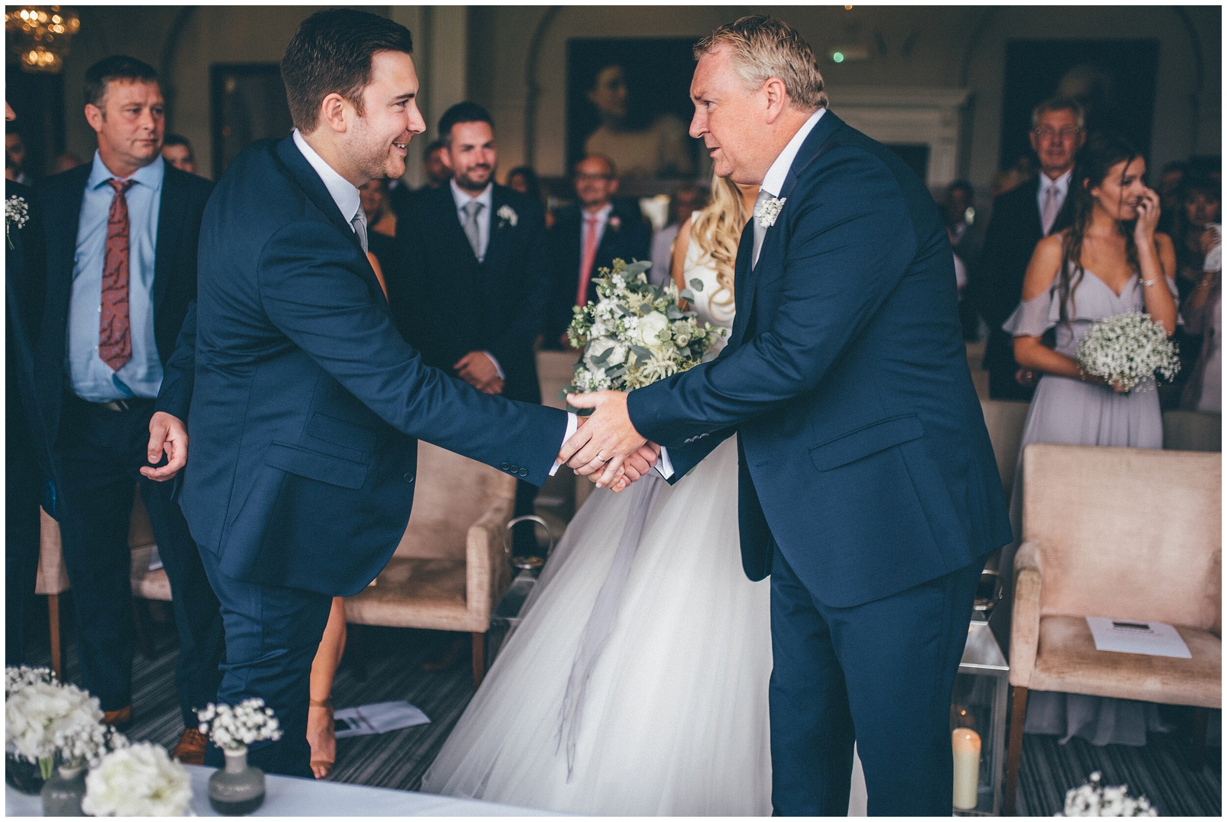 Father of the bride and groom shake hands before the wedding ceremony at The Belsfield, Laura Ashley hotel in the Lake District.