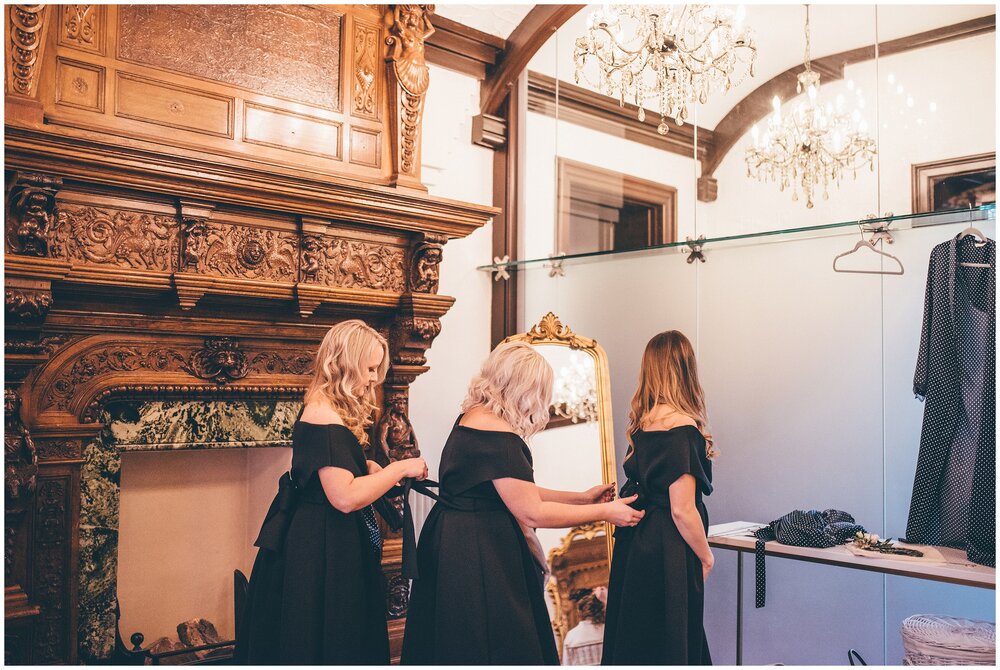 Bridesmaids all help each other in their black ASOS dresses at Tyn Dwr Hall.