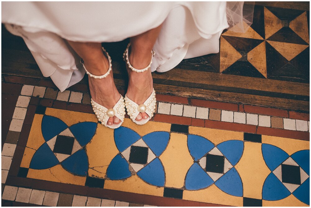 Stunning bridal pearl Jimmy Choo wedding choosing on detailed tiled floor at Tyn Dwr Hall in Wales.
