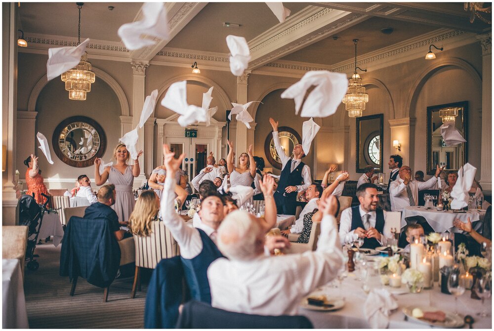 Wedding guests all cheer and throw their napkins in the air at The Belsfield Hotel in the Lake District.
