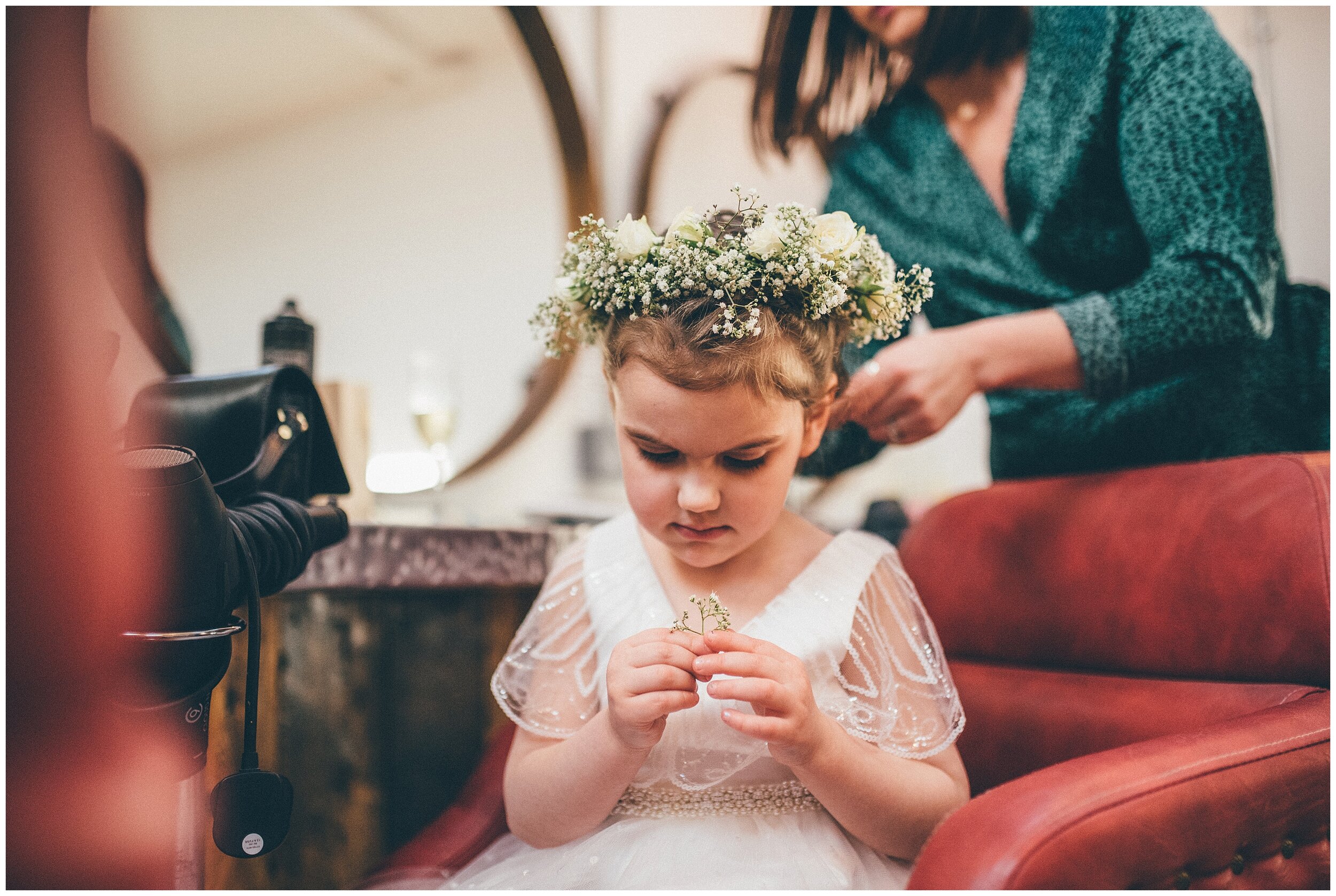Cute little flower girl checks her flower crown at Owen House Wedding Barn in Cheshire.