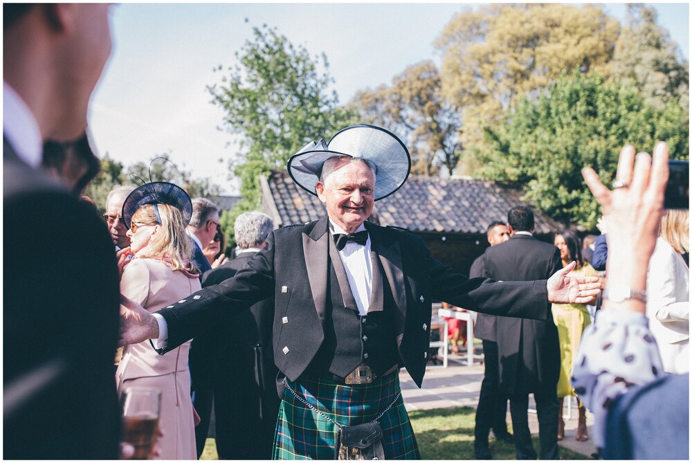 Wedding guest poses for photograph with his wife's hat on.