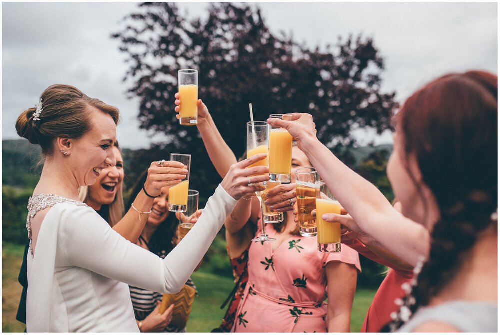 Bride cheers with her friends at her summer wedding in the Lake District.