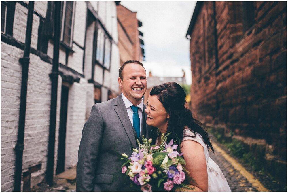 Newlyweds laugh with each other in cobbled streets of Chester after their Oddfellows wedding.