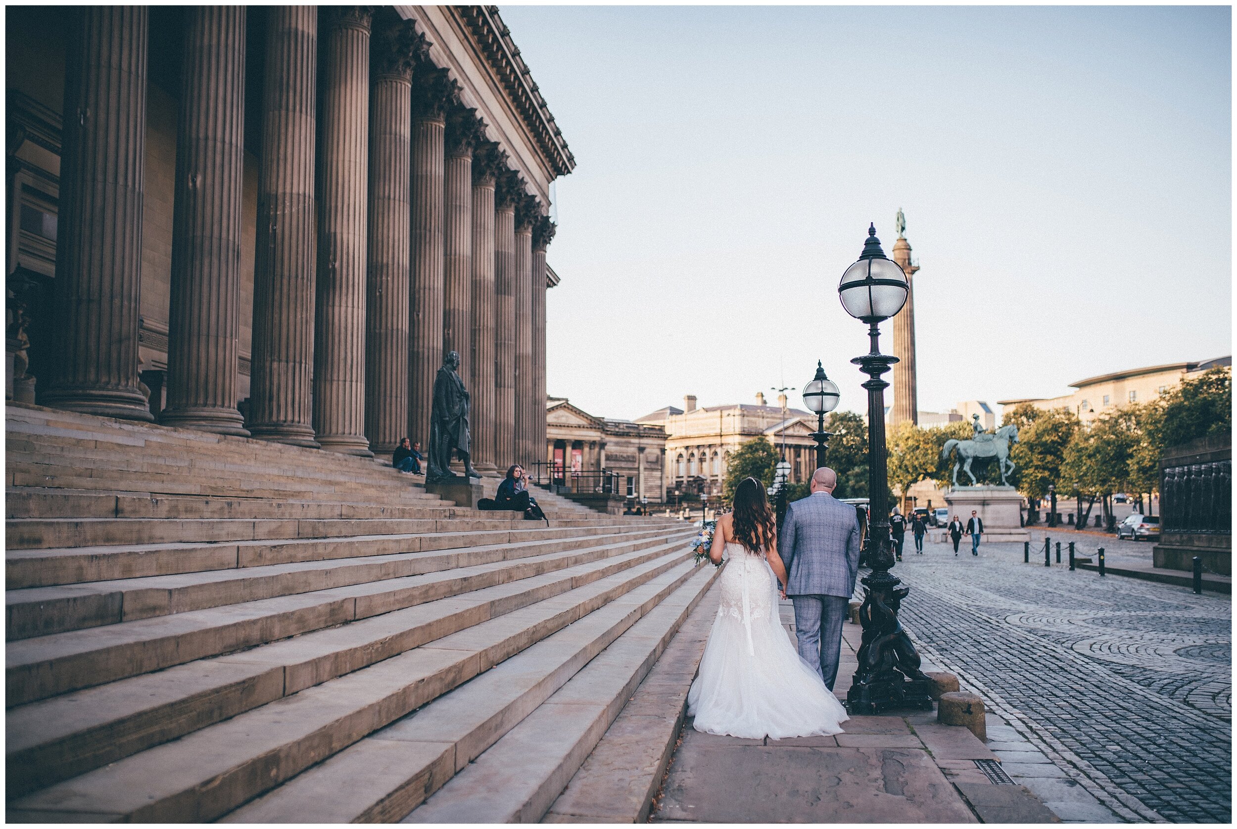 Bride and Groom walk by St George's Hall in Liverpool city centre after their wedding.