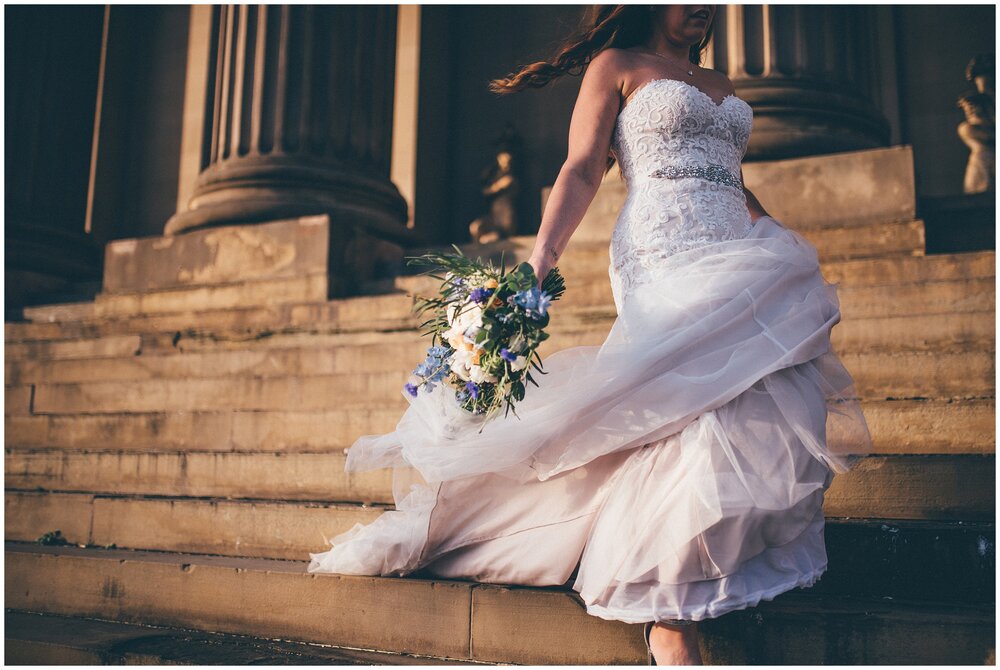 Stunning lace and beaded wedding gown in the golden hour as bride walks down the steps of St Georges Hall in Liverpool City Centre.