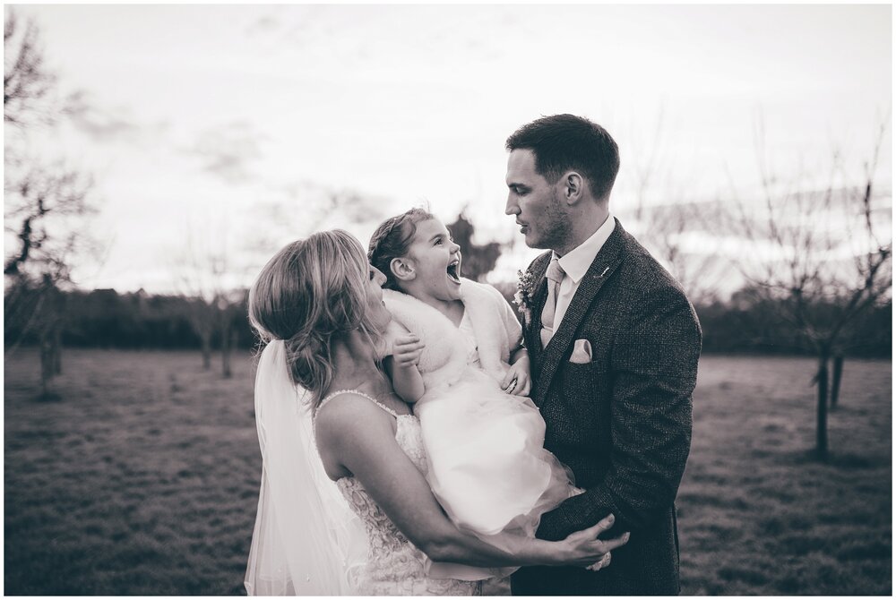 Bride and groom have a photograph taken on their wedding day with their little girl at Cheshire wedding.