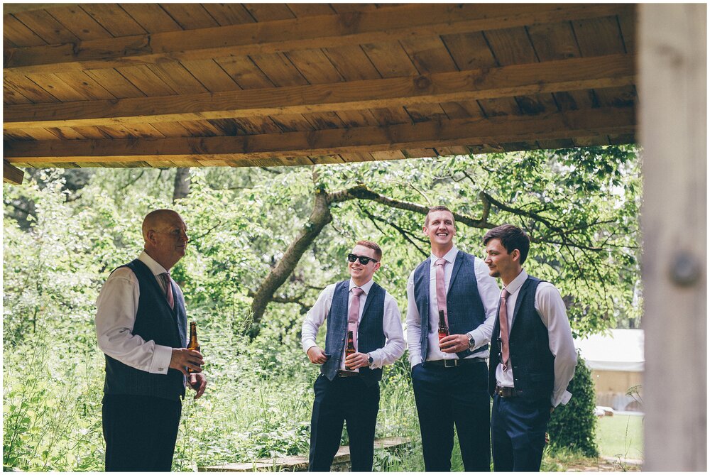 Groomsmen chat together in rustic wedding venue, ahead of the ceremony.