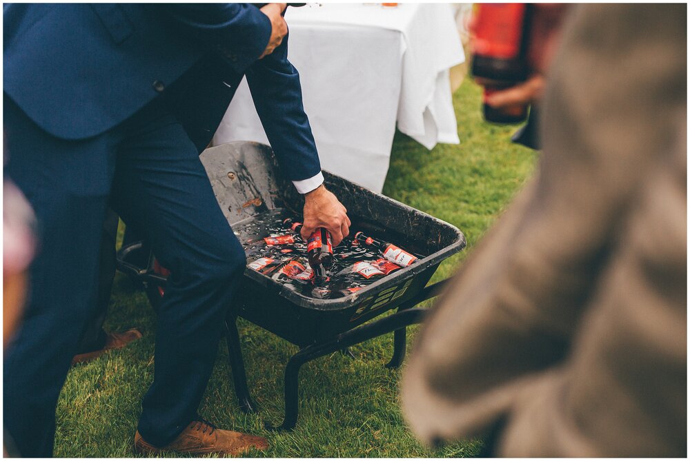 wedding guests help themselves to bottles of Budweiser from a wheel barrow.