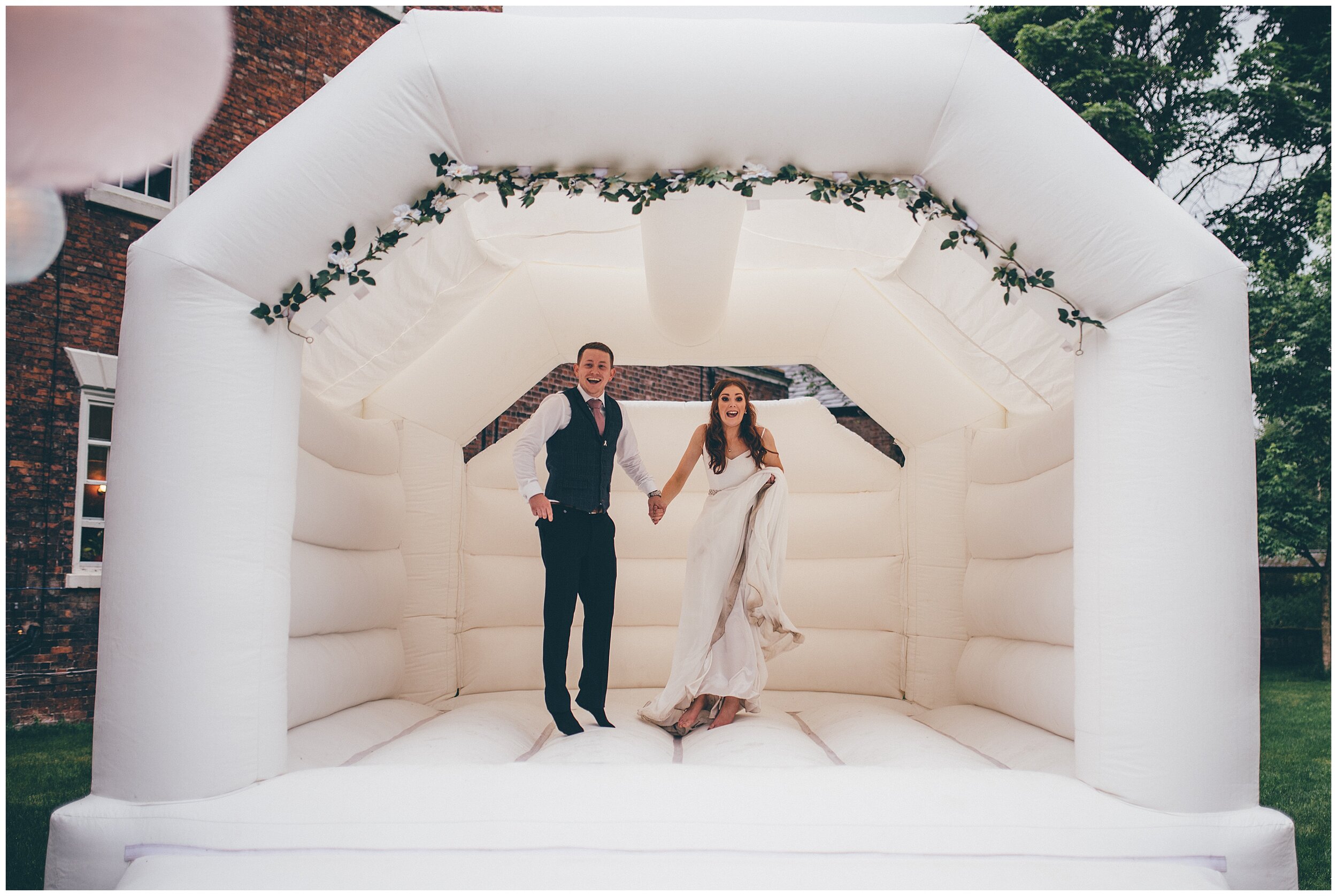 Bride and groom bounce on their bouncy castle during their festival themed wedding in Cheshire.