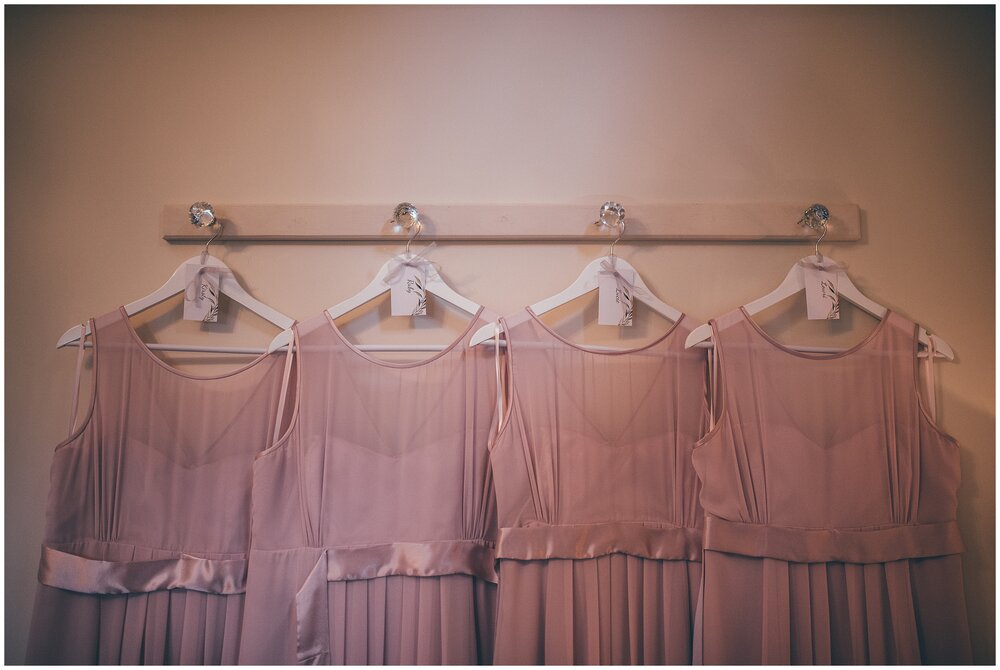 Blush pink Maids to measure bridesmaid dresses hung up before the wedding.