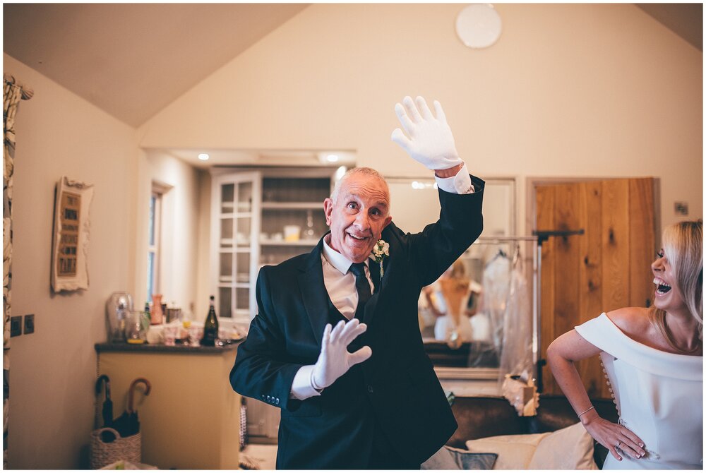 Bride's dad wears white gloves before fastening his daughter into her incredible Suzanne Neville gown.