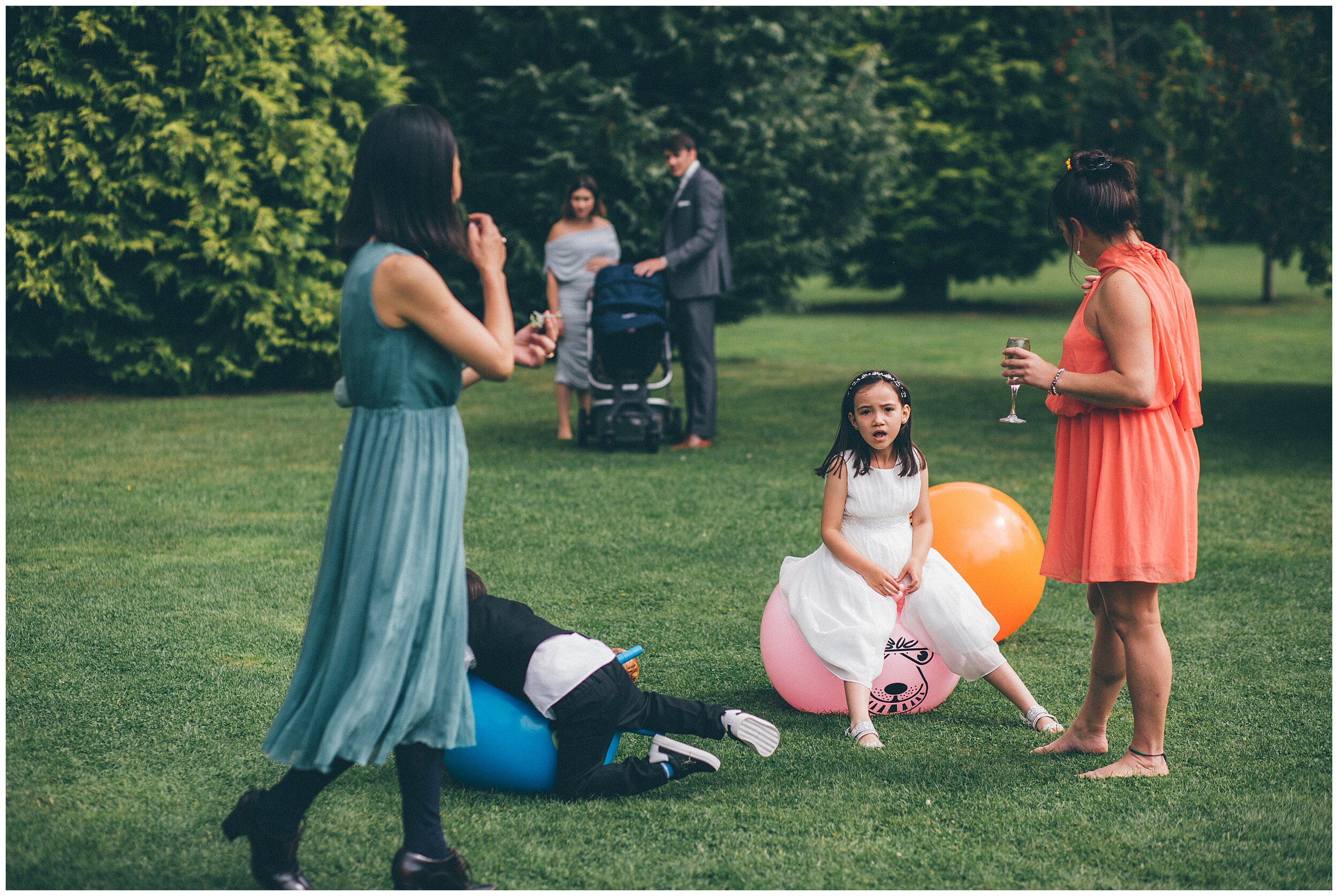 Children playing on space hoppers at summer wedding.