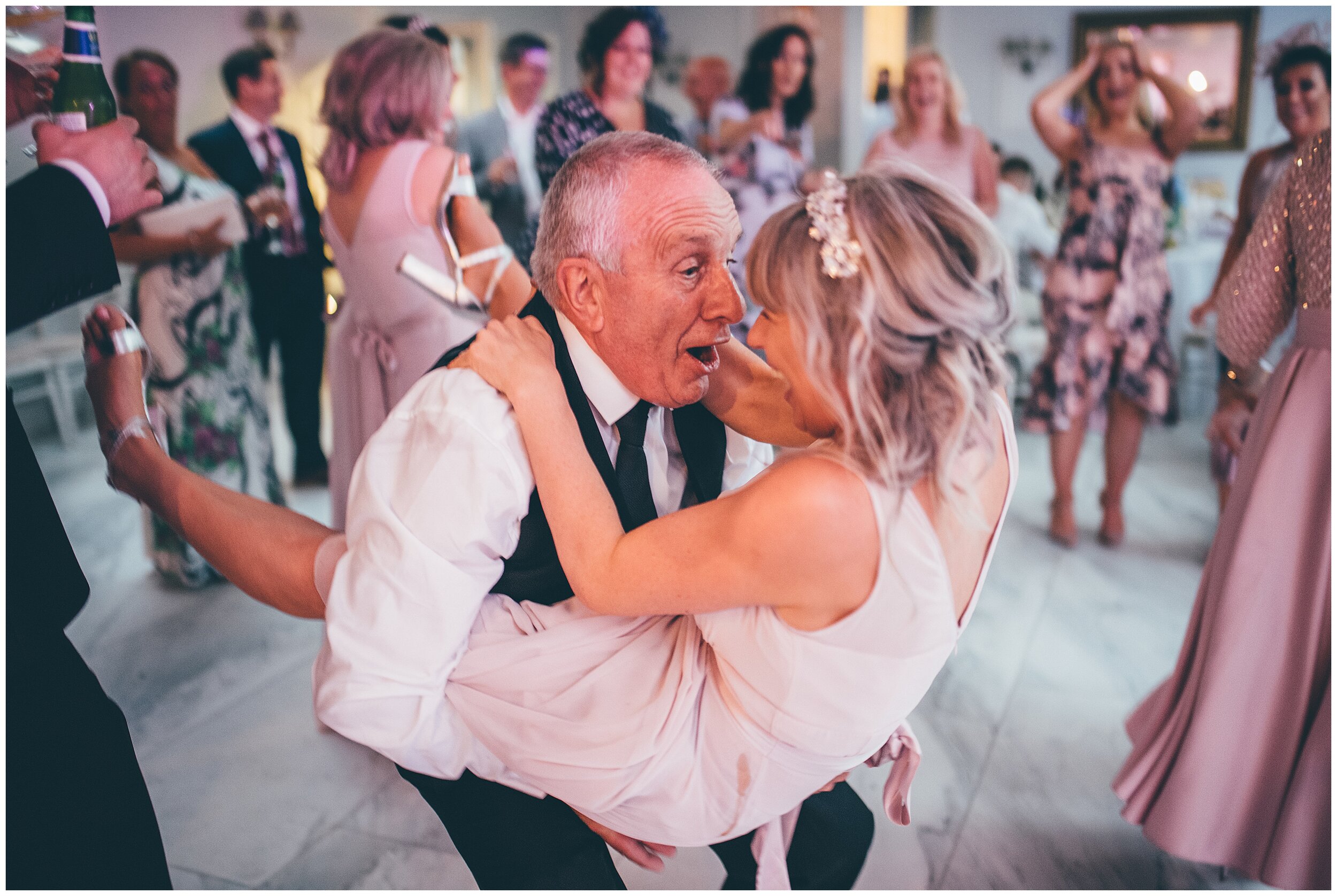 hilarious photograph of the brides dad lifting up one of the bridesmaids.