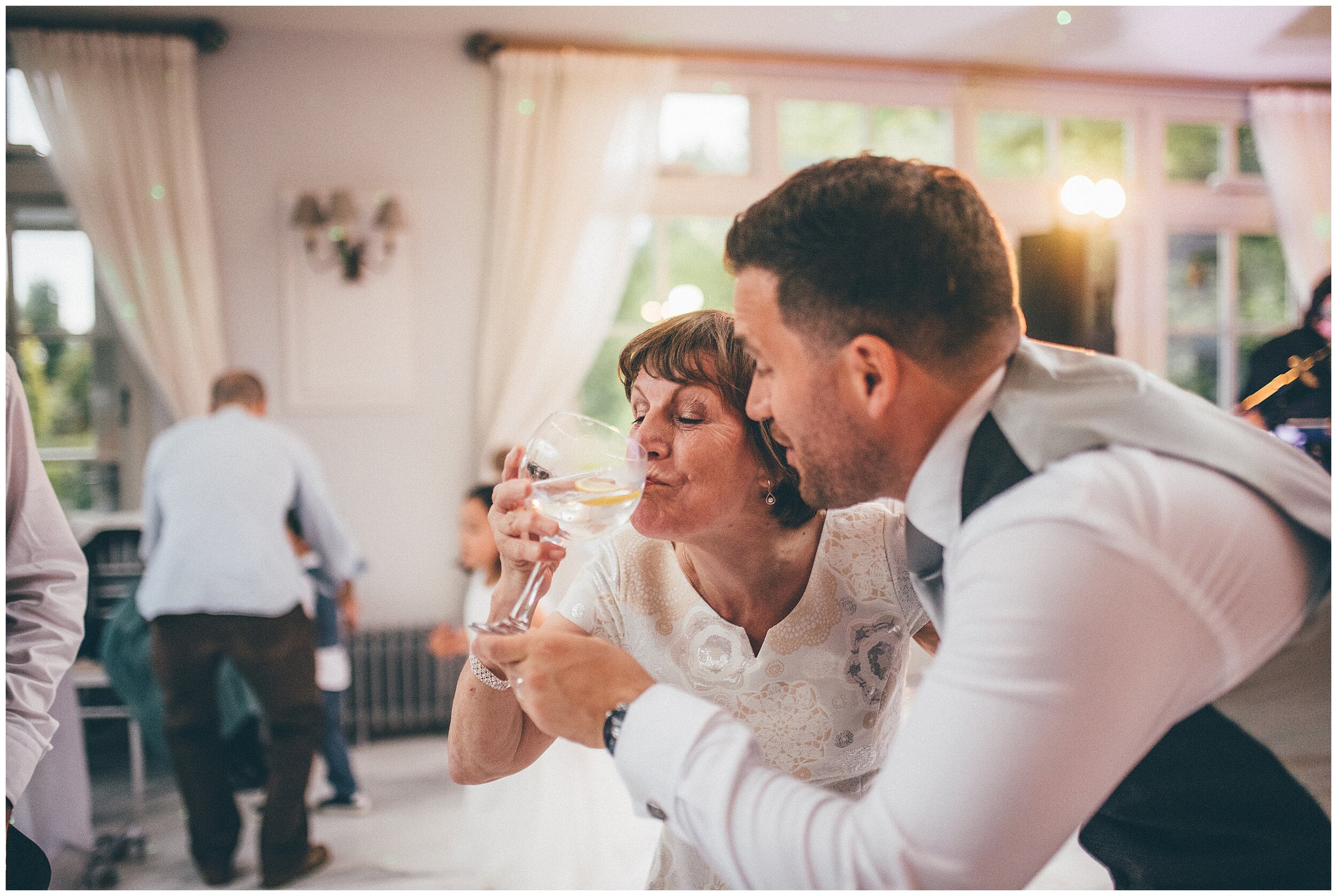 Groom encourages his mum to drink a gin and tonic on the dance floor.