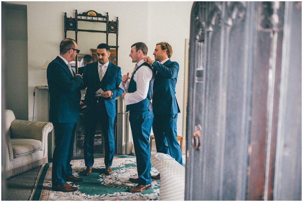 Groom chats with his groomsmen at Wirral wedding venue.
