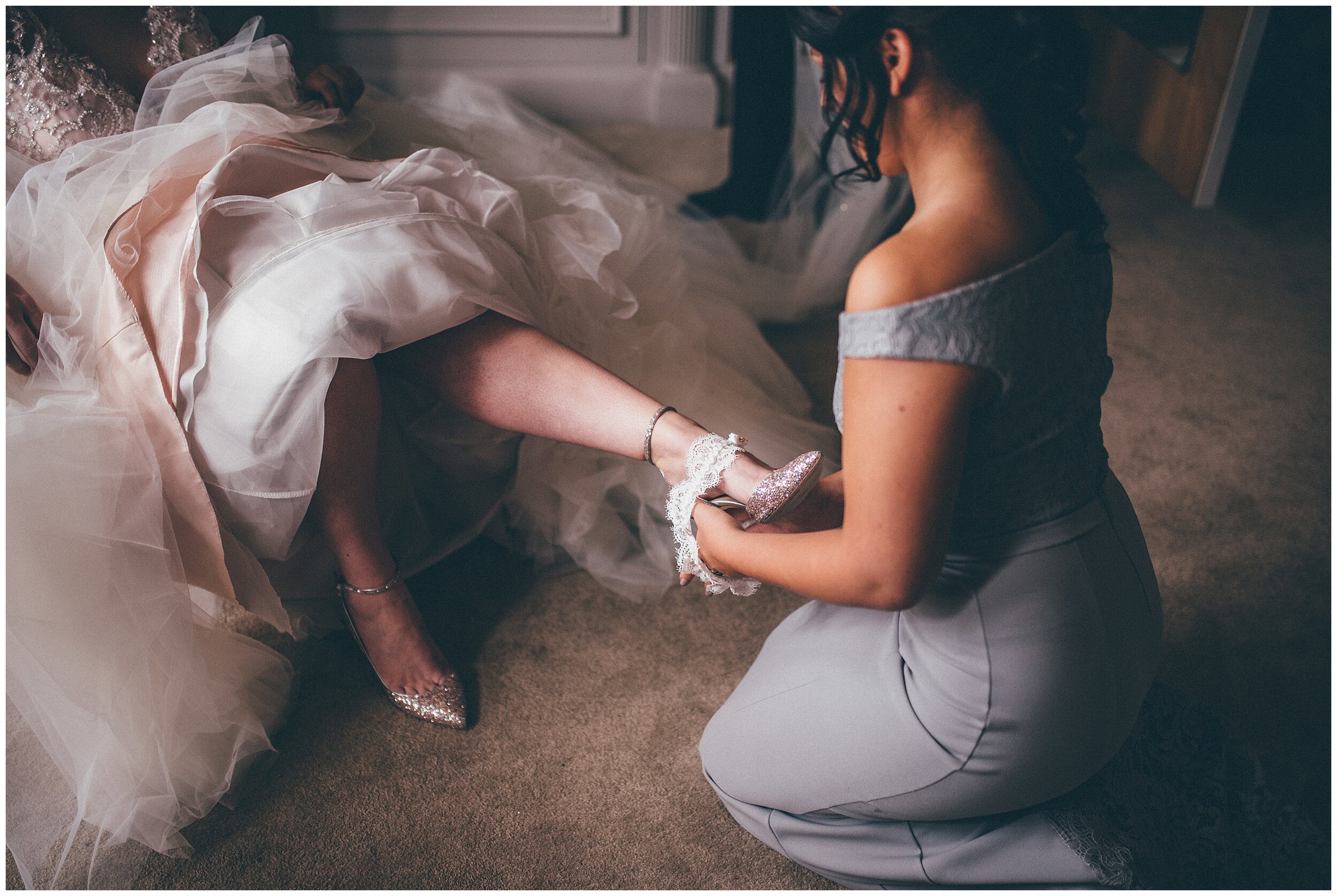 Bridesmaid helps bride with her garter
