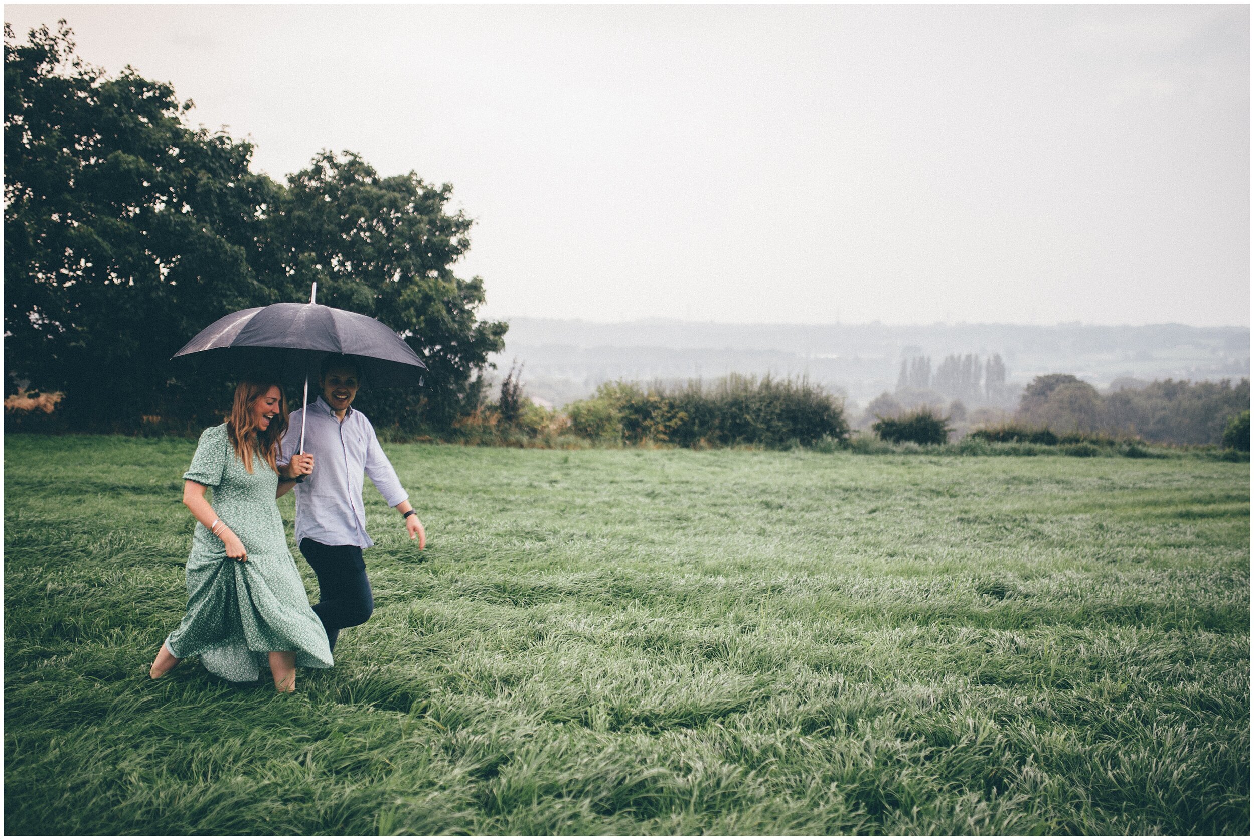 Couple walk through rainy field in Cheshire.