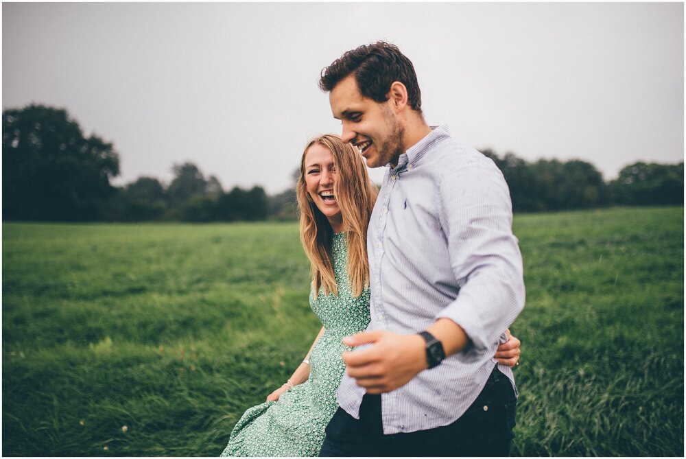 Young couple laugh together walking through a field in Cheshire.