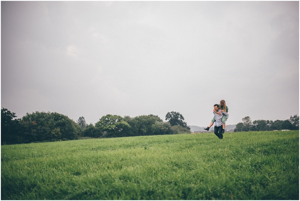 Man gives girlfriend a piggy back through a field in Cheshire.