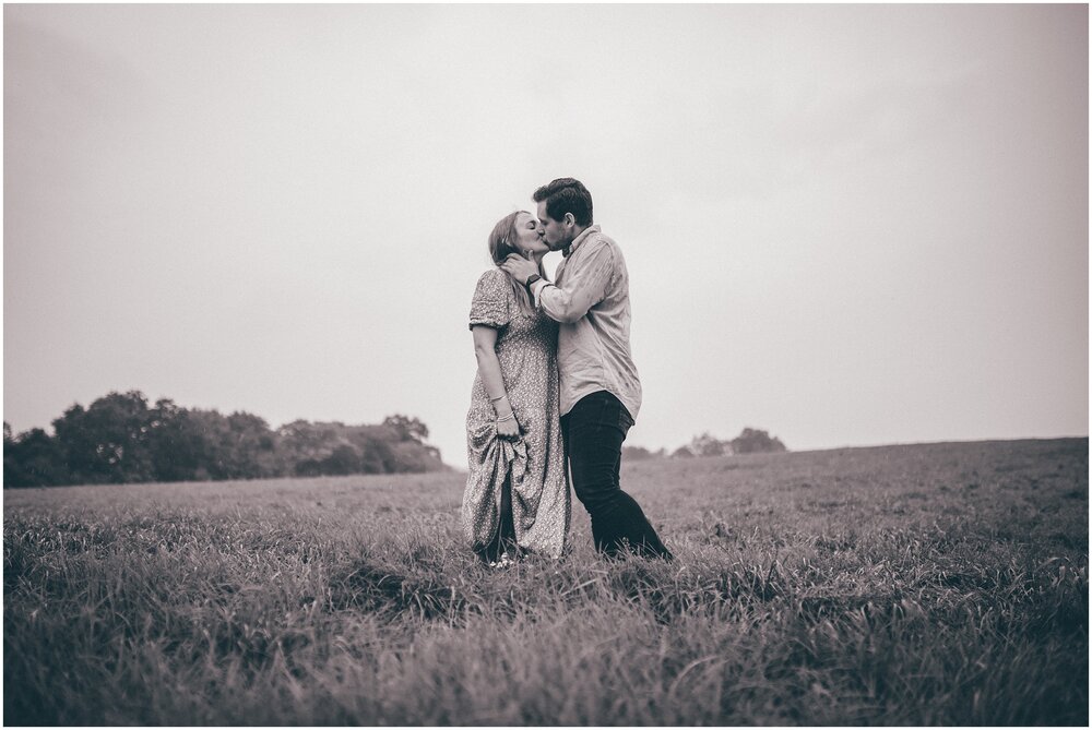 Young couple kiss in a field in Cheshire in the rain photoshoot.